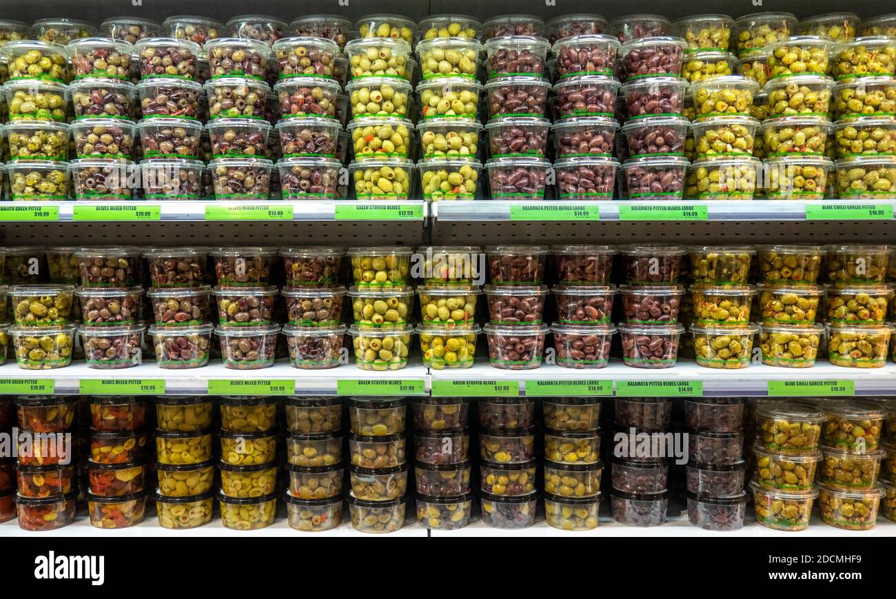 Variety of olives prepacked in plastic tubs on display and for sale in