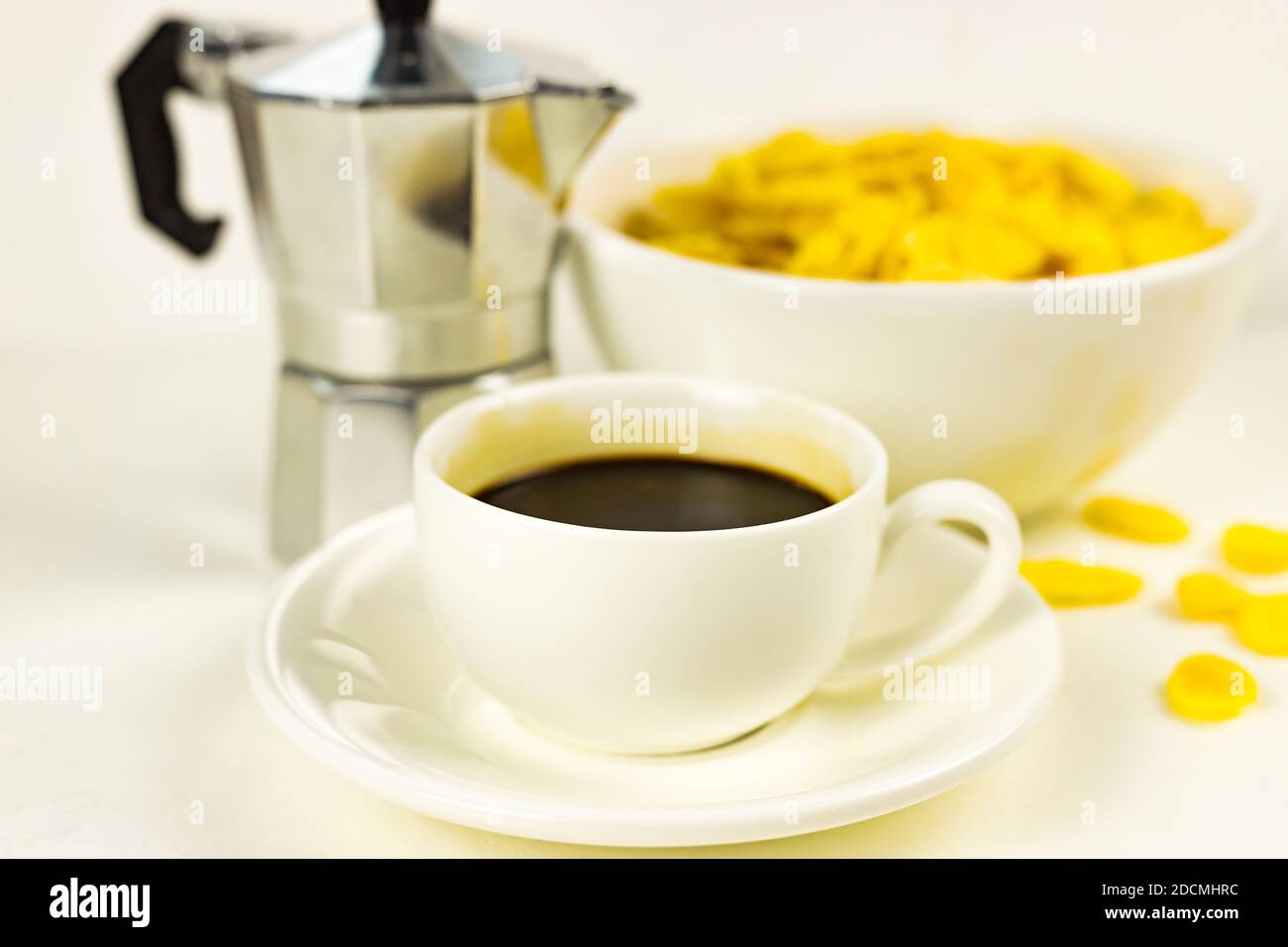 Corn flakes in white bowl, cup of black coffee espresso, geyser coffee