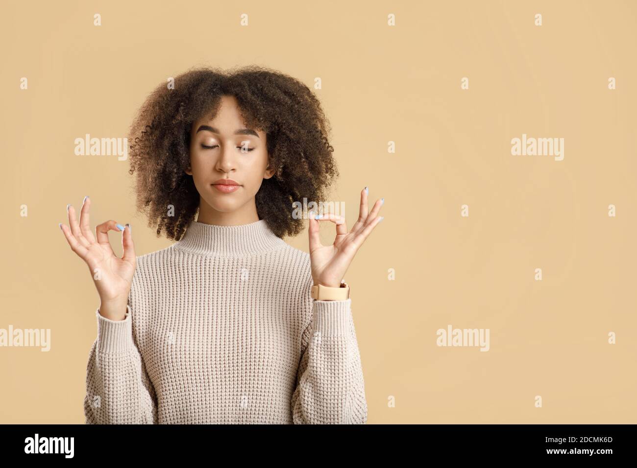 Cheerful curly young african american female with closed eyes practicing yoga and breathing Stock Photo