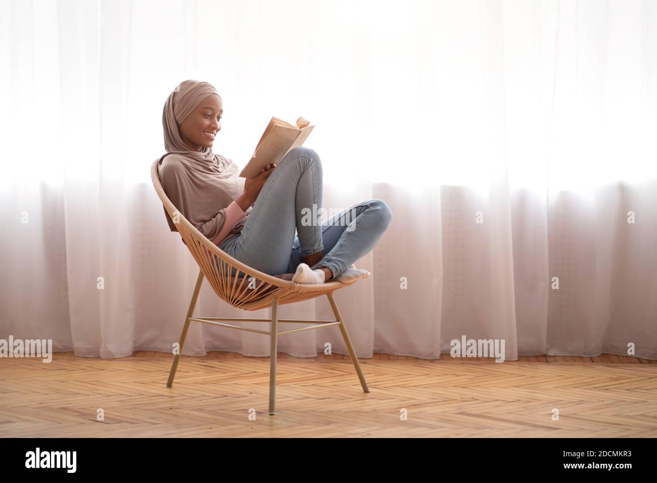 Black Muslim woman in traditional headscarf relaxing in comfy armchair ...