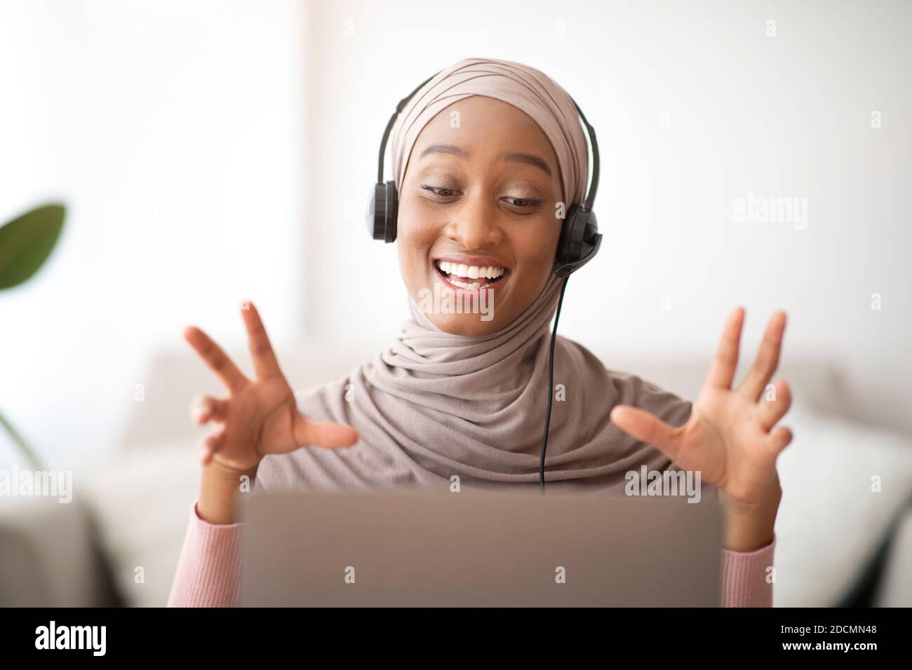 Attractive Muslim black woman in hijab wearing headphones ...