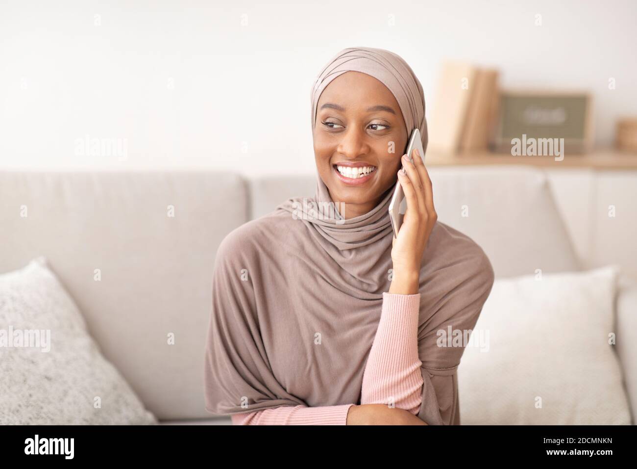 Smiling black lady in hijab speaking on smartphone at home Stock Photo ...