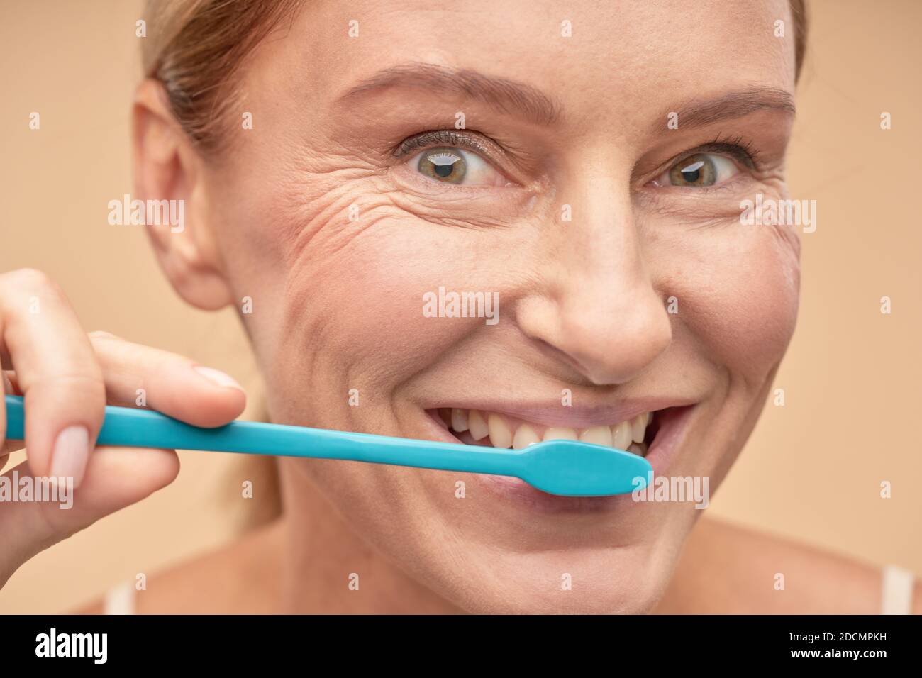 Dental hygiene. Smiling mature lady taking care of the oral cavity