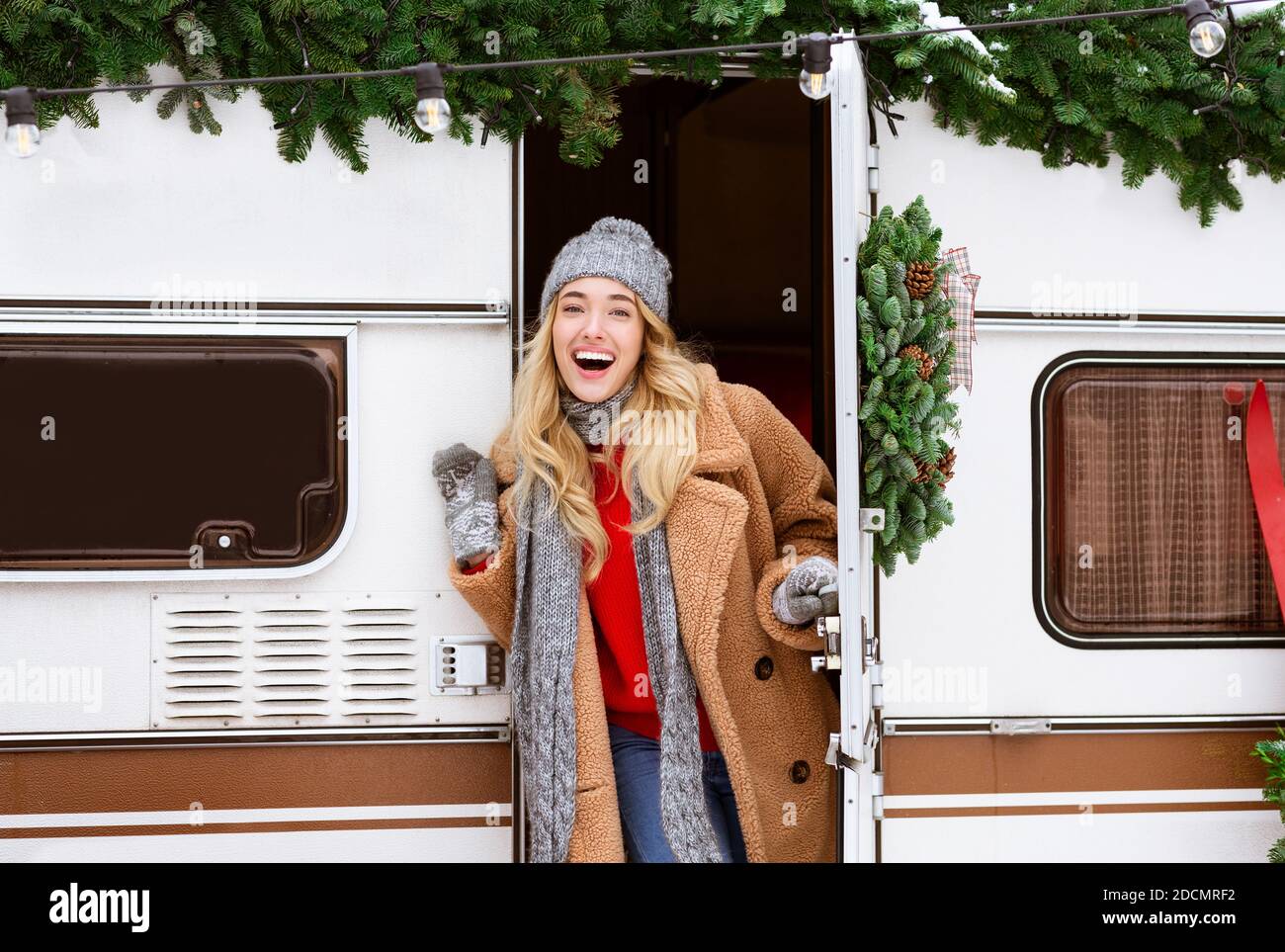 Winter Travels. Excited Blonde Woman Going Out Of Modern Campervan, Camping Outdoors Stock Photo