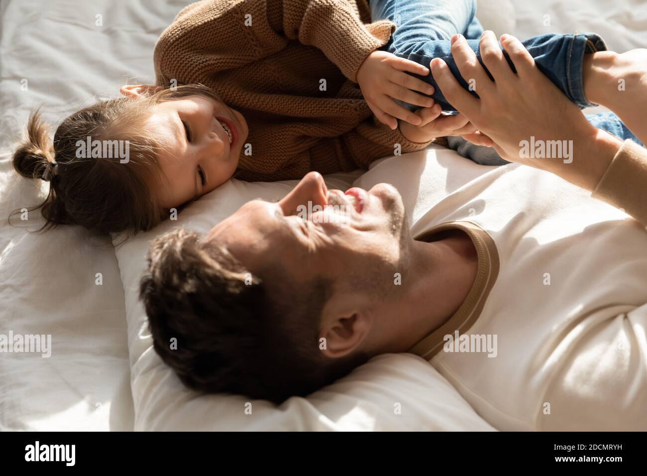 Dad spend time with little daughter lying together in bed Stock Photo