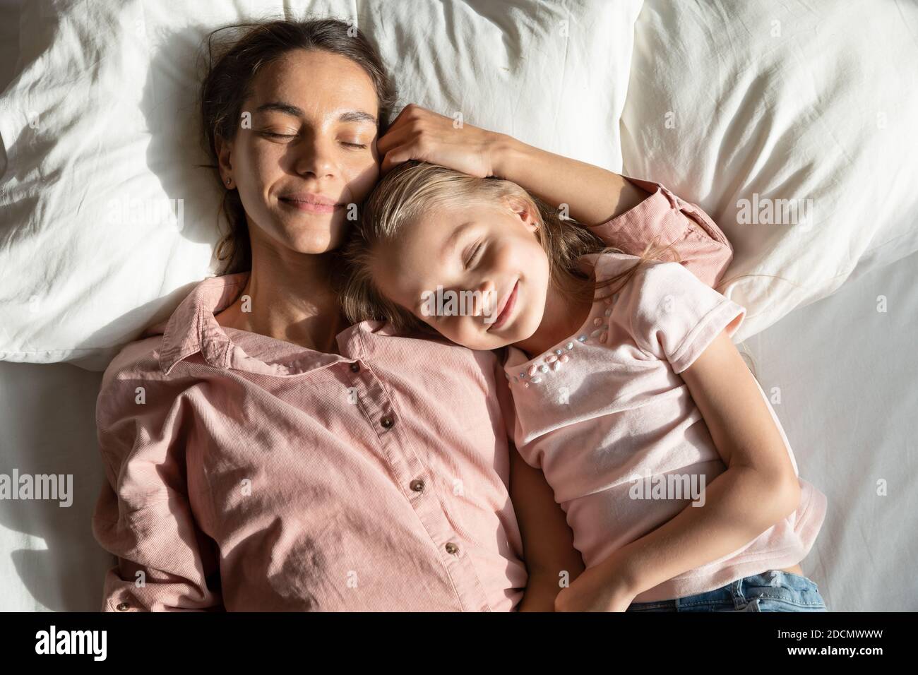 Calm mother and daughter sleeping together in bed, above view Stock Photo