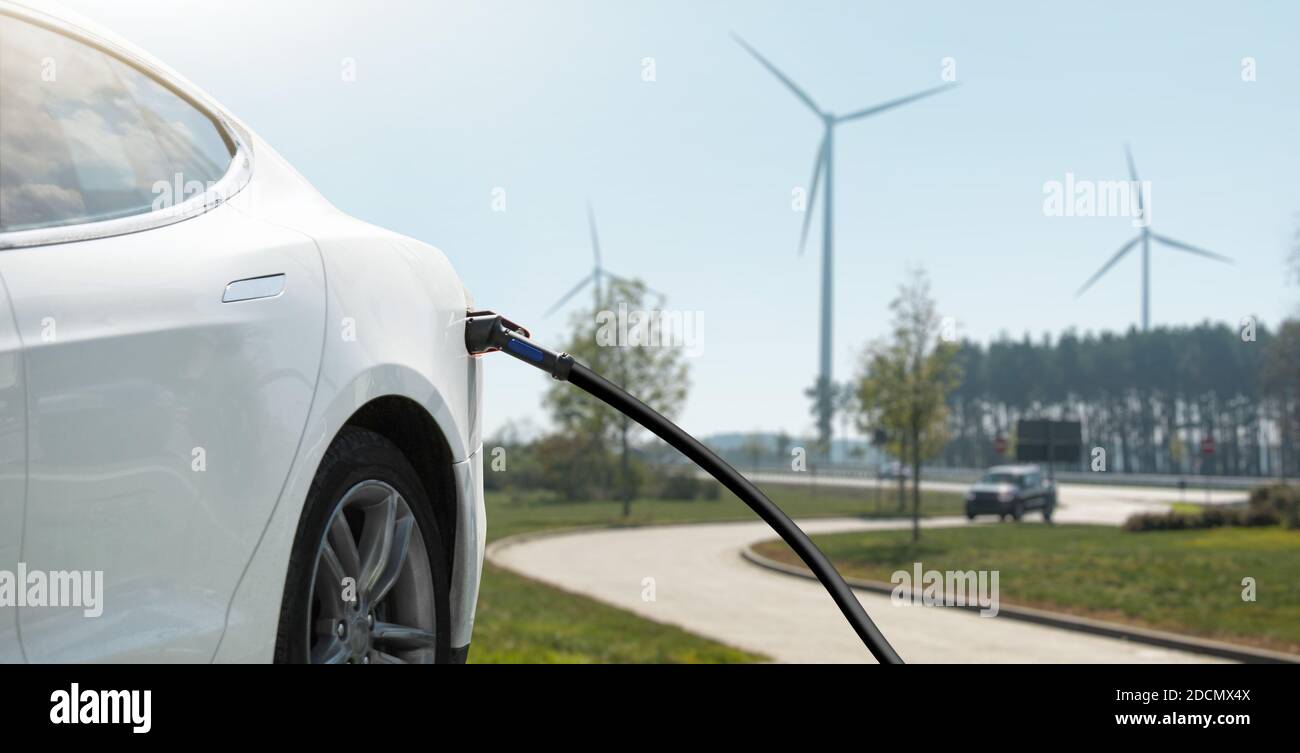 Electric car with charging plug on a background of wind turbines Stock