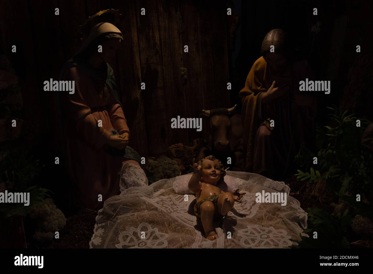 Nativity scene with baby Jesus lying down and Mother Mary and father Joseph looking after. Christian religion traditional decoration, low key concept Stock Photo