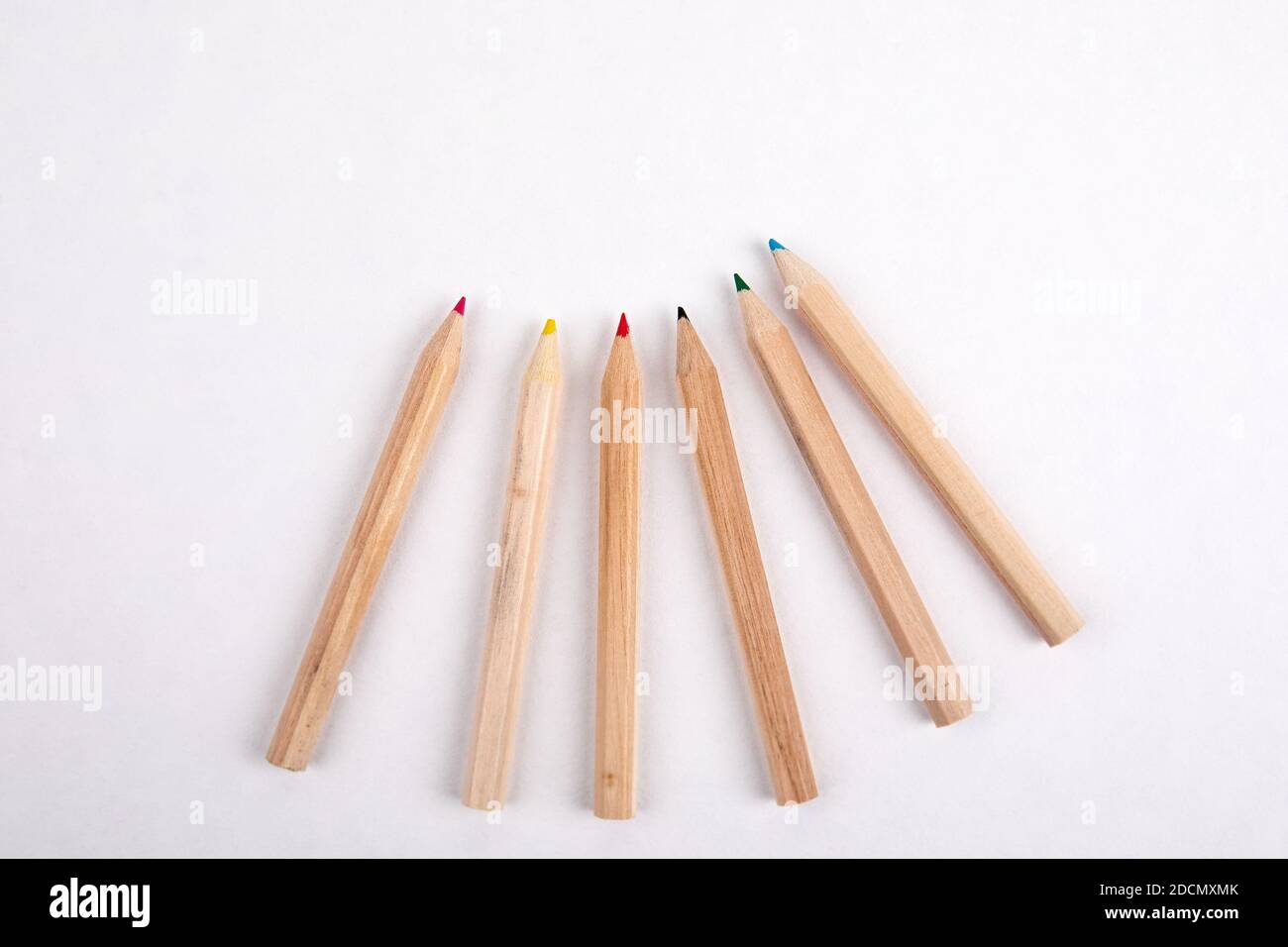 Wooden colored pencils on a white sheet of paper. Creativity, education