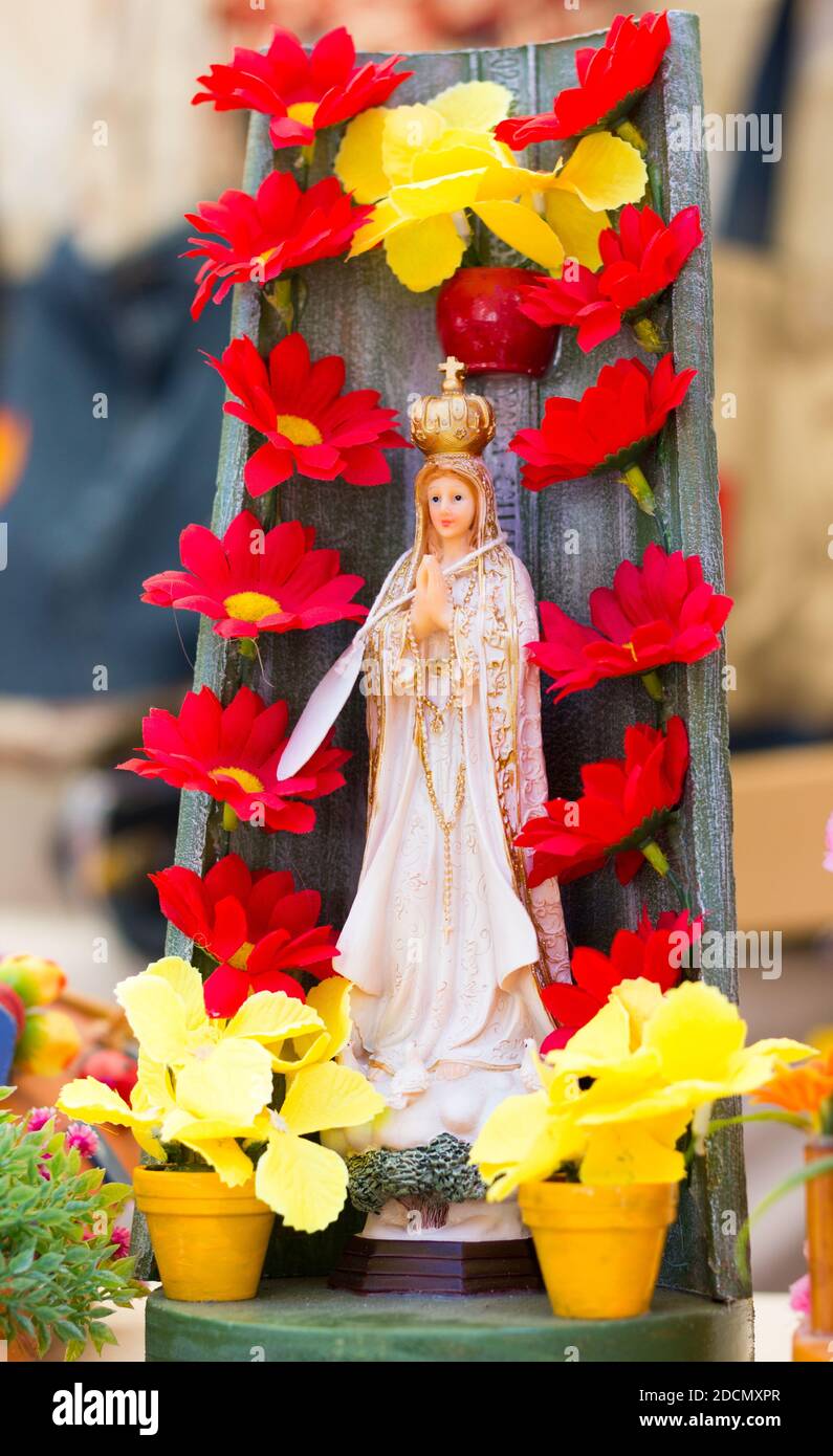 Virgin Mary statue figure with red flowers and yellow clay pots ...