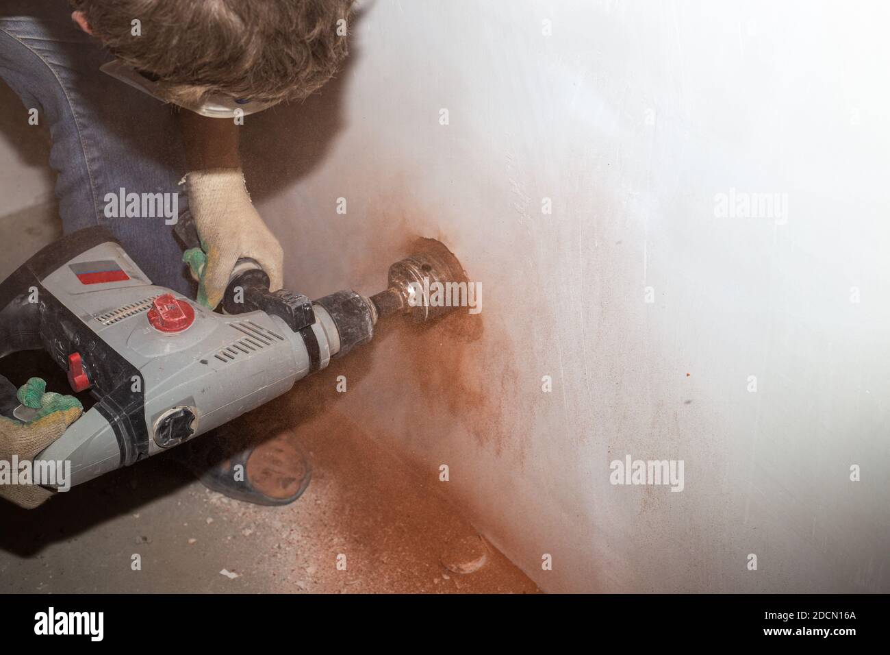 a worker with a drill with a nozzle drills a hole for an electrical