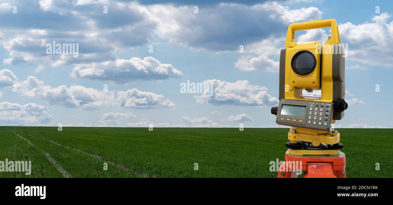 Theodolite on a background of green field. Construction industry Stock Photo