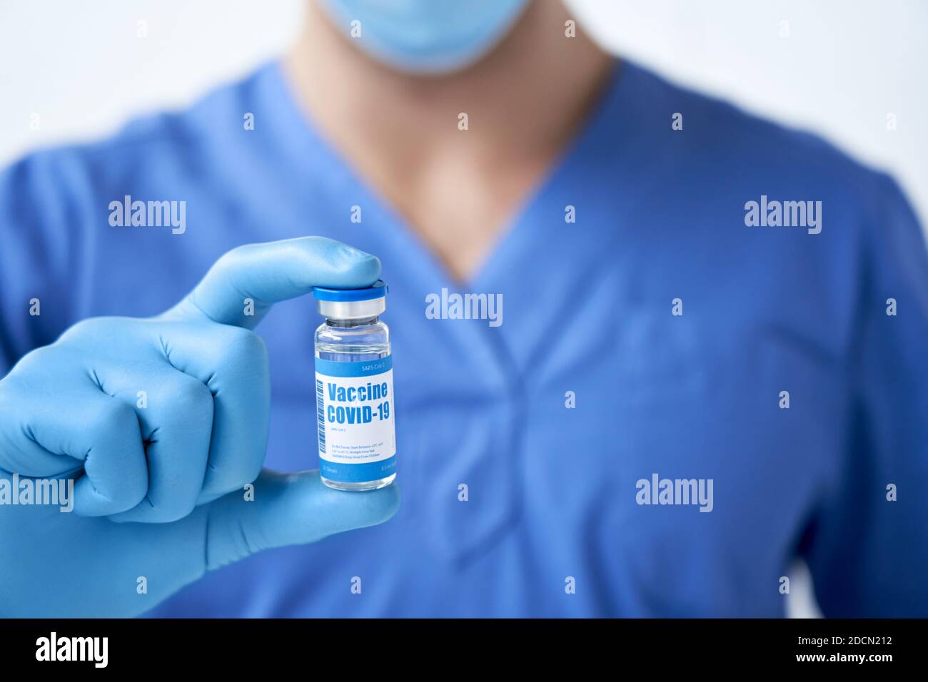 Doctor wears mask and gloves holding vial with covid 19 corona virus vaccine. Stock Photo