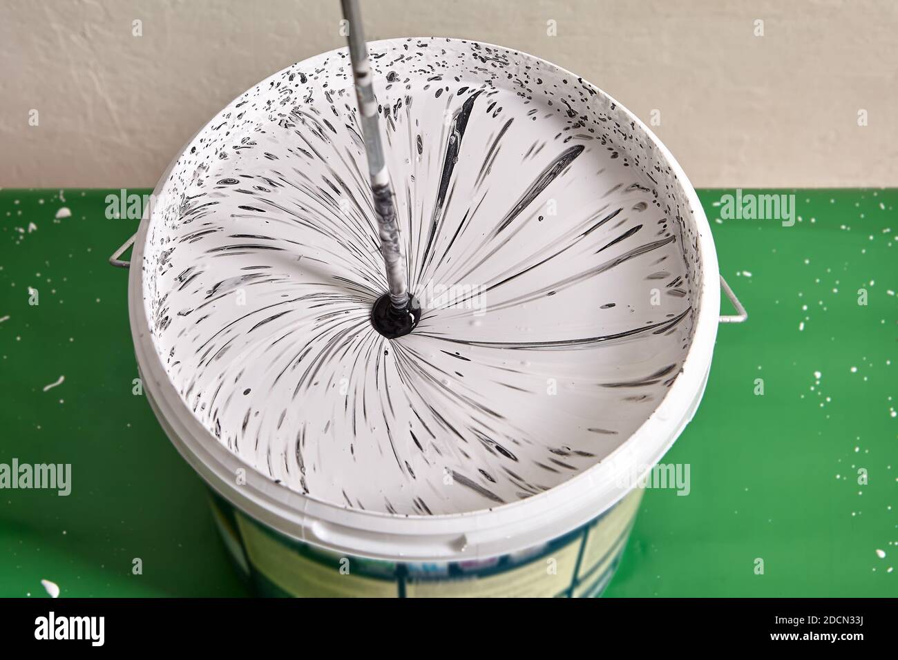 House painter mixes paints for coloring wall using drill. Stock Photo