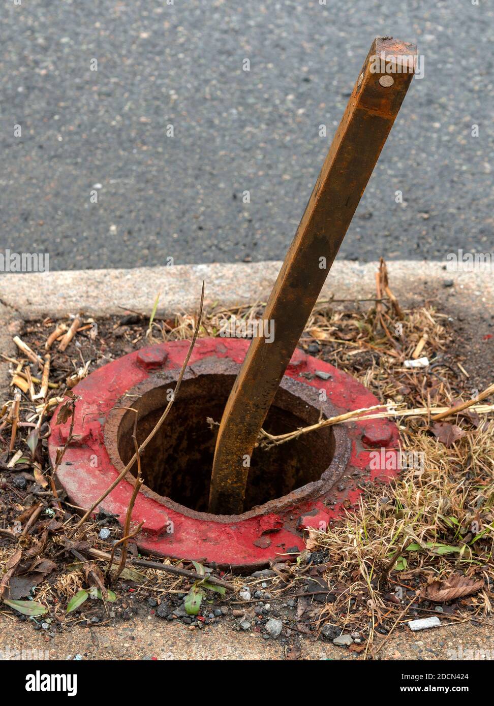 A broken fire hydrant. The actual hydrant is missing, the supporting base around the hole, and valve stem are still present. The valve stem is bent. F Stock Photo