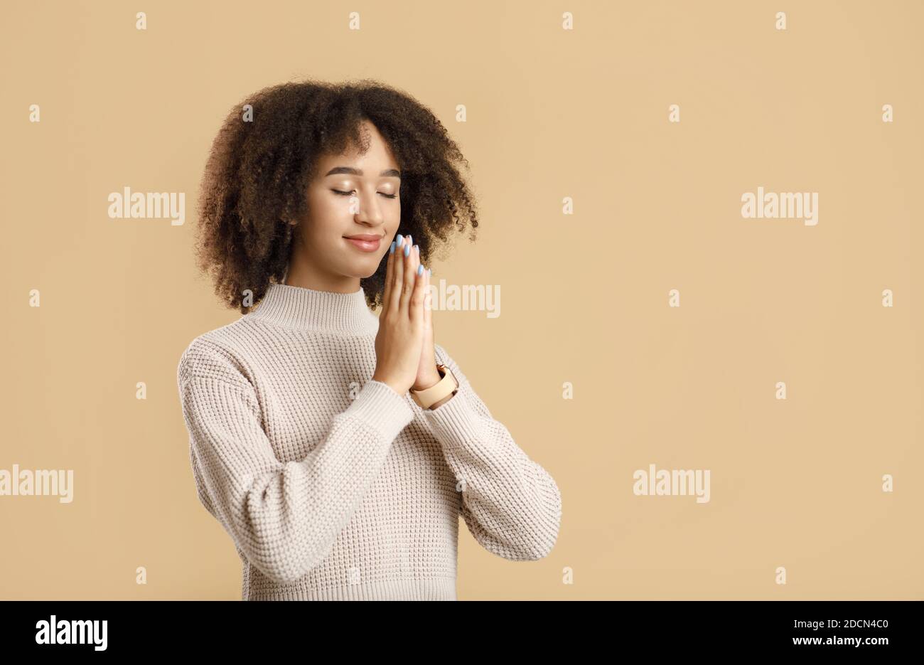Portrait of young woman keeping palms together and praying, meditating Stock Photo