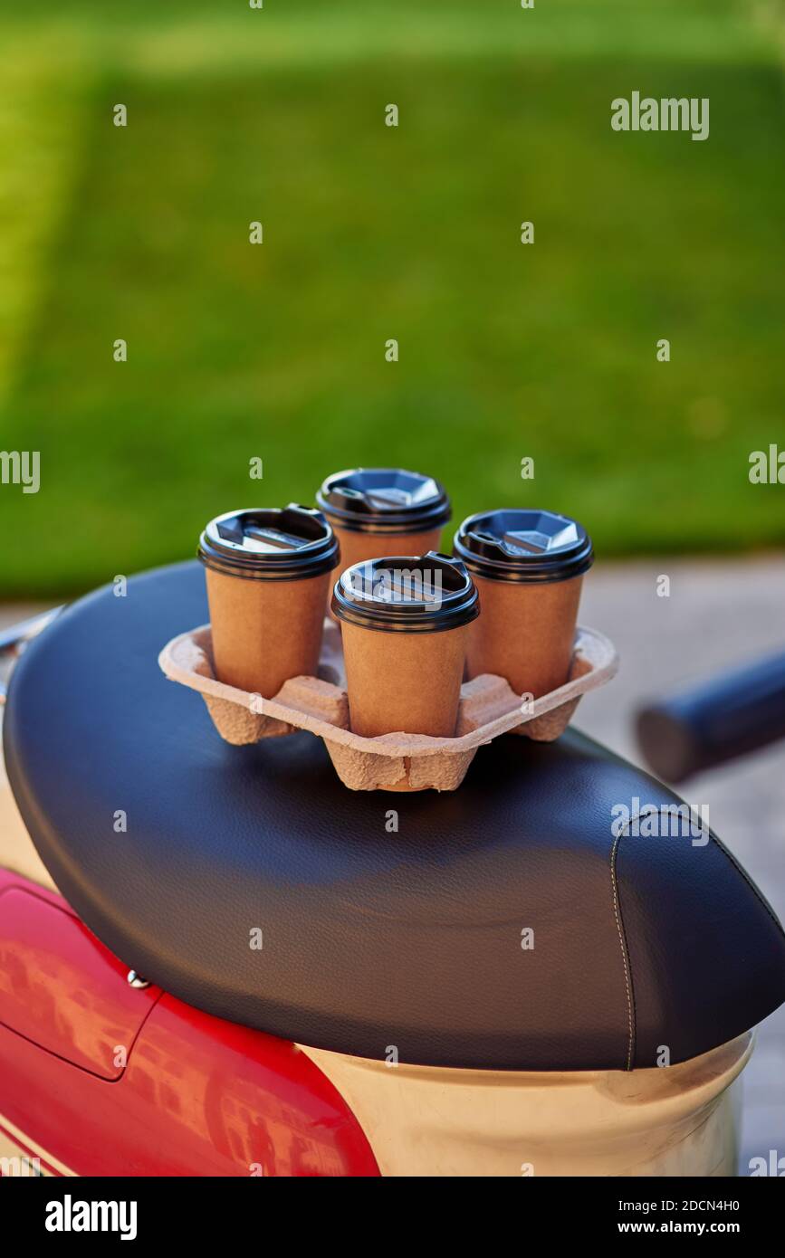 Four paper coffee cups standing on scooter, selective focus. Food