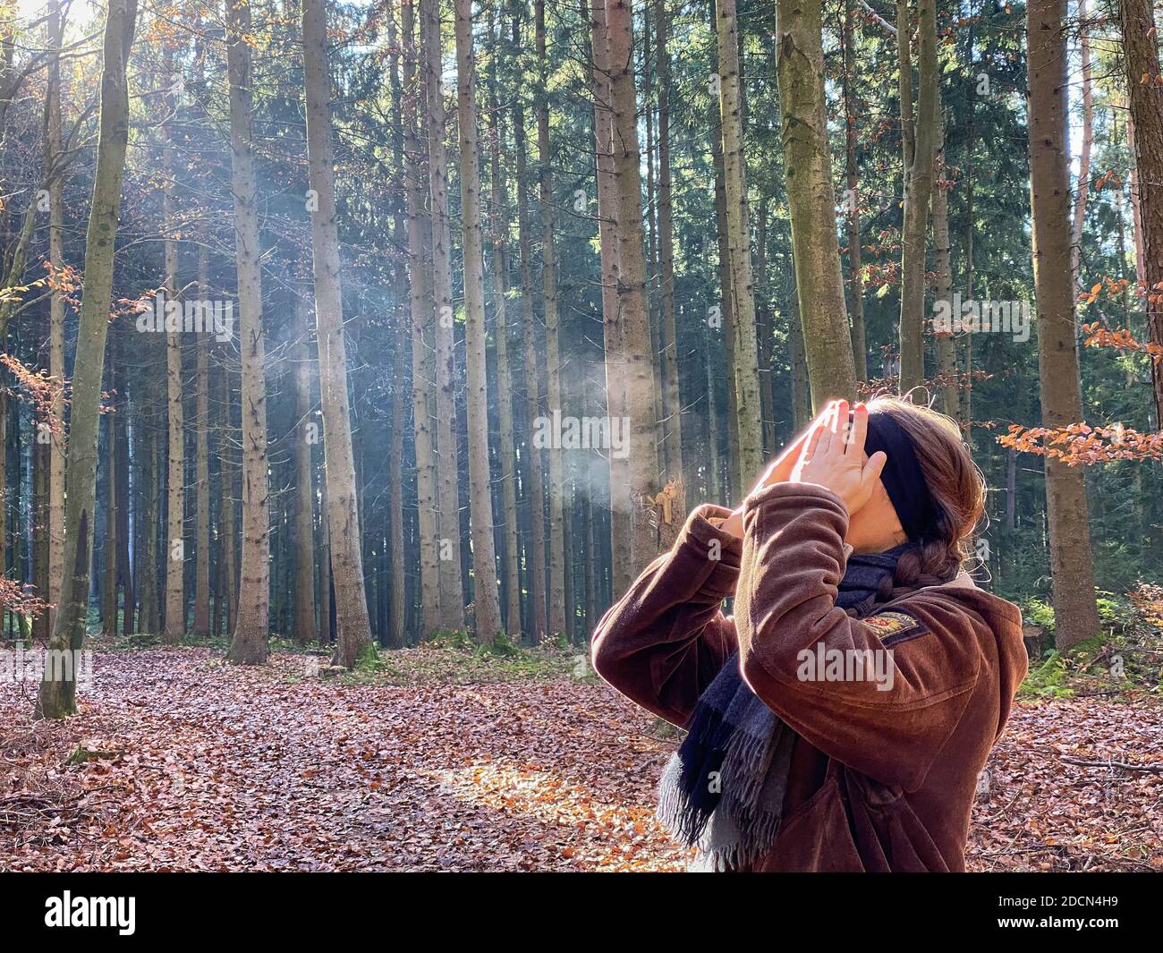 A woman is walking through the forest in autumn, forest bathing, or shinrin-yoku on November 22, 2020 in Pfaffenhofen a.d.Ilm, Bavaria, Germany. Forest bath – has the power to counter illnesses including cancer, strokes, gastric ulcers, depression. The term emerged in Japan in the 1980s as a physiological and psychological exercise called shinrin-yoku (“forest bathing” or “taking in the forest). © Peter Schatz / Alamy Stock Photos MODEL RELEASED Stock Photo