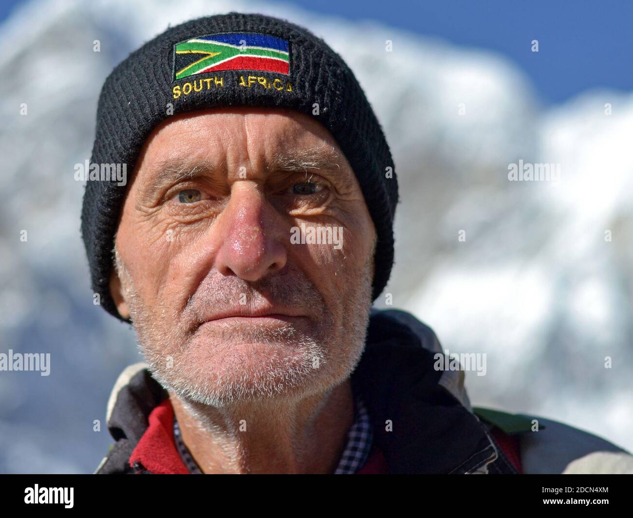 Elderly unshaved Caucasian male trekker with South African flag on woolen cap poses for the camera at Gorak Shep near Everest Base Camp. Stock Photo