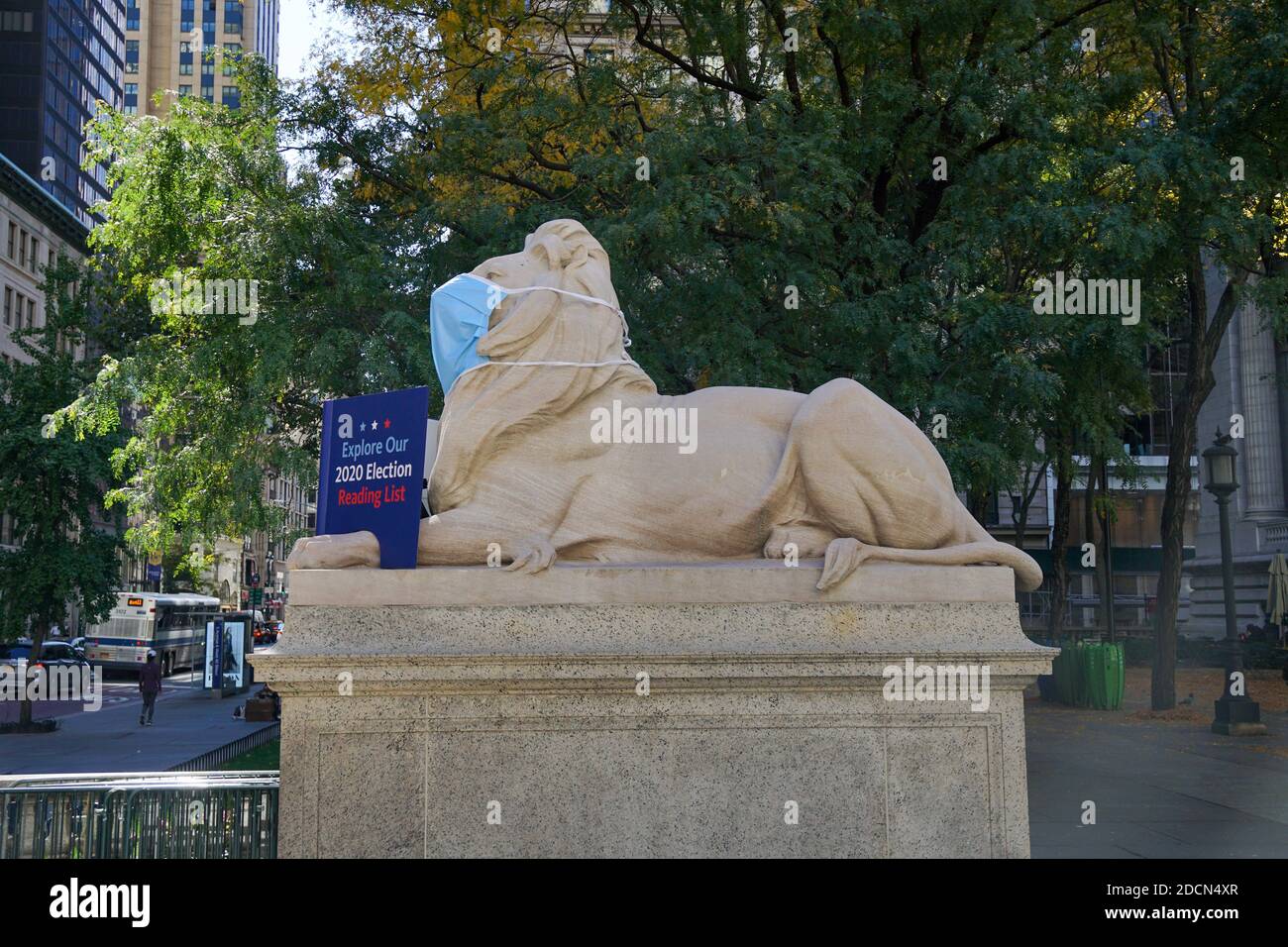 Lion in front of New York Public Library wearing mask, holding a book 'read, think vote' Stock Photo