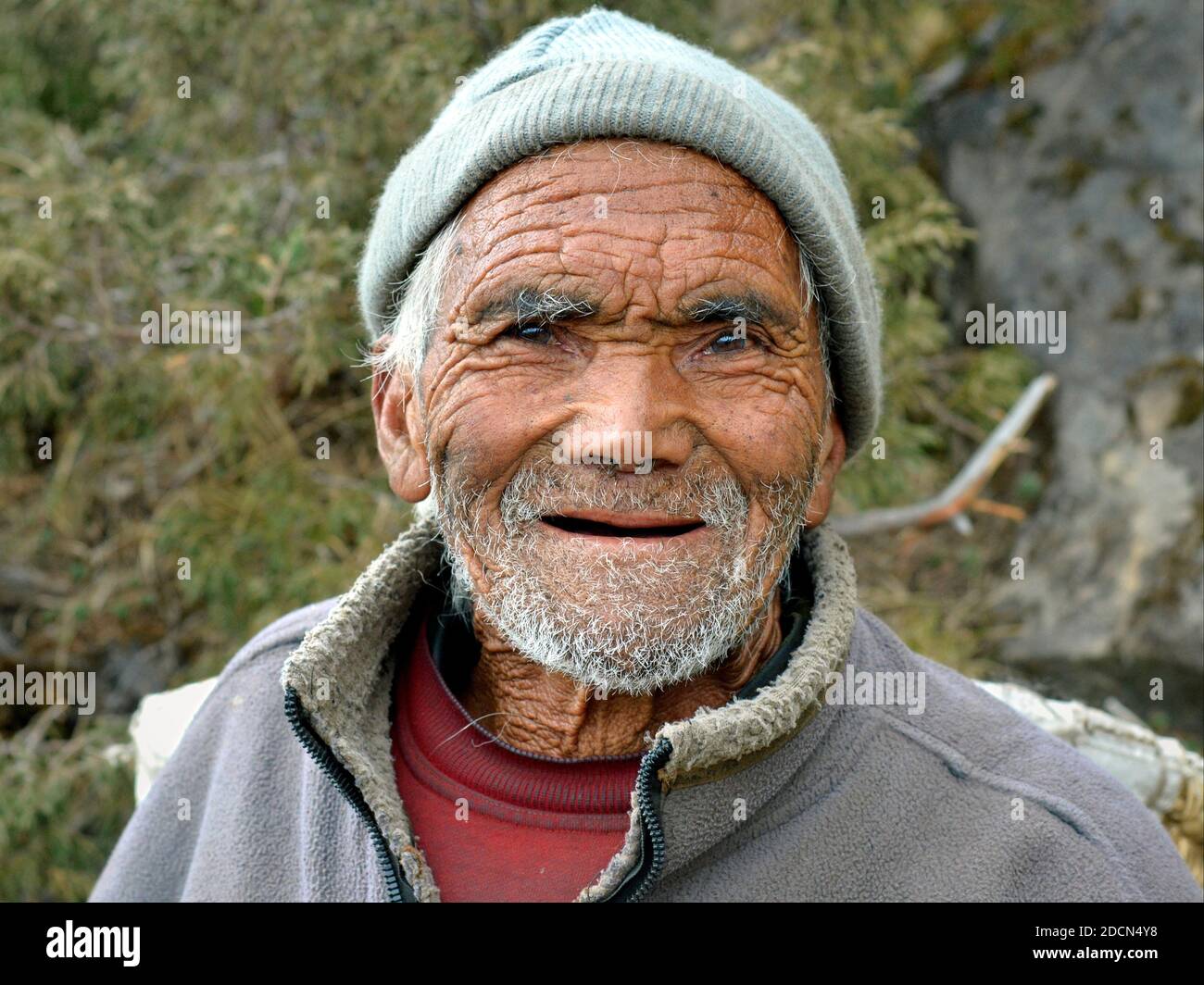Very old toothless Nepali Sherpa man with deep wrinkles all over his lived-in face poses for the camera on Everest Base Camp Trek. Stock Photo