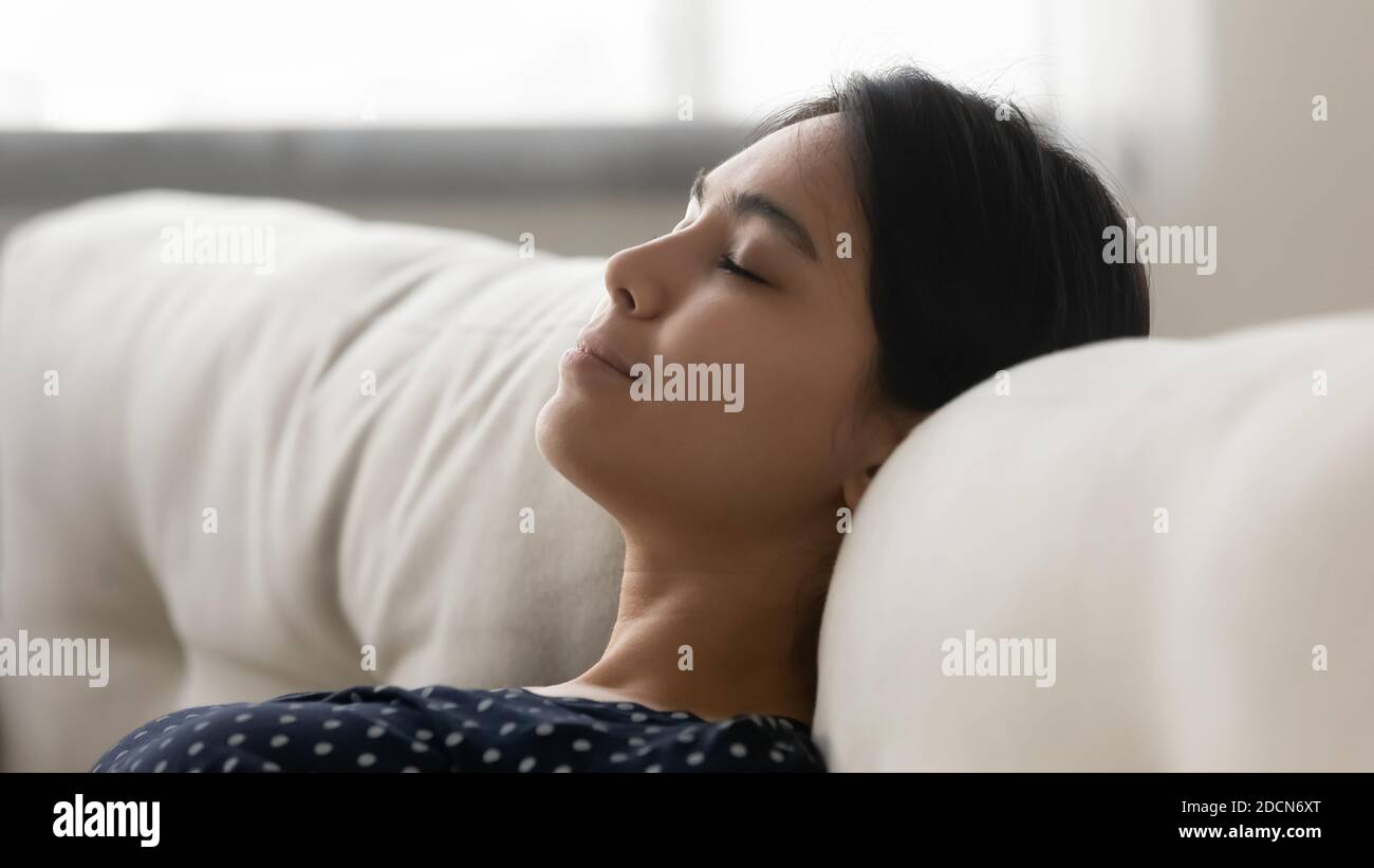 Close up tranquil calm Asian young woman resting on sofa Stock Photo