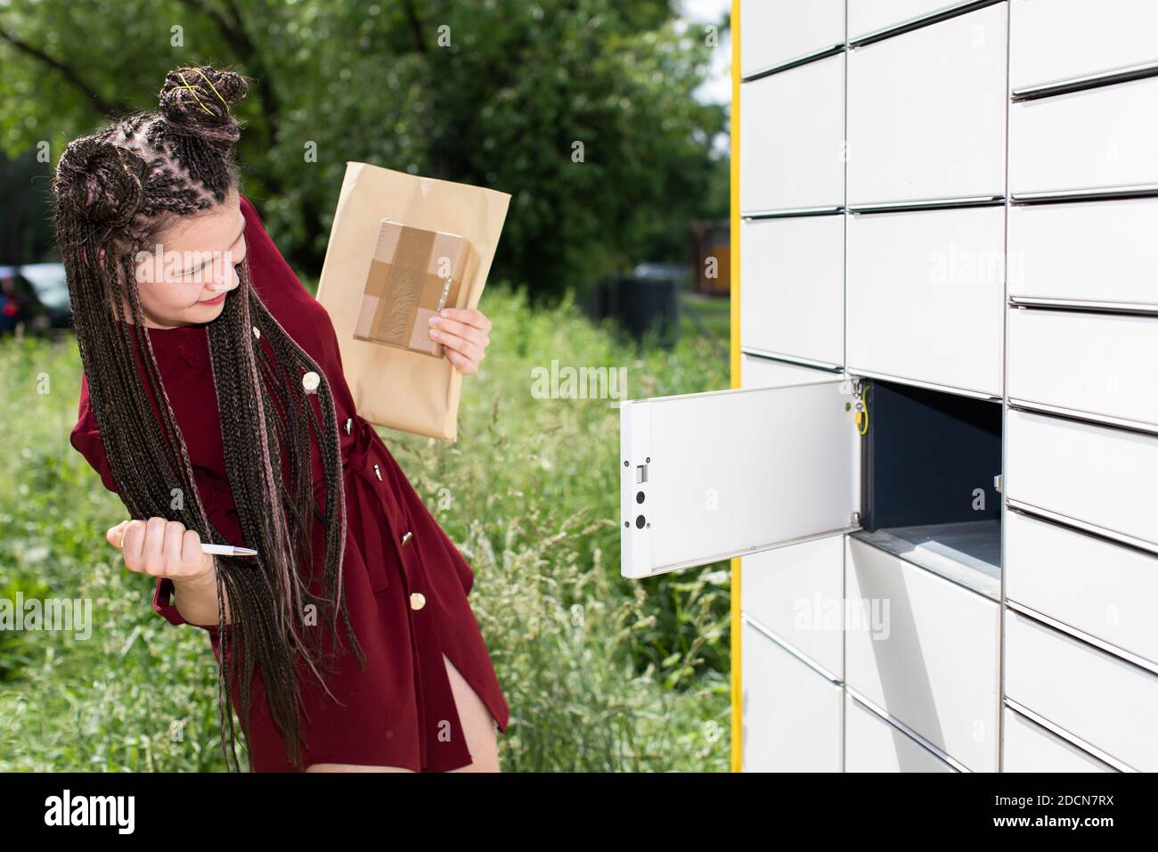 He carefully checks the opened mailbox. Young teenage girl with an interesting hairstyle. African braids. Stock Photo