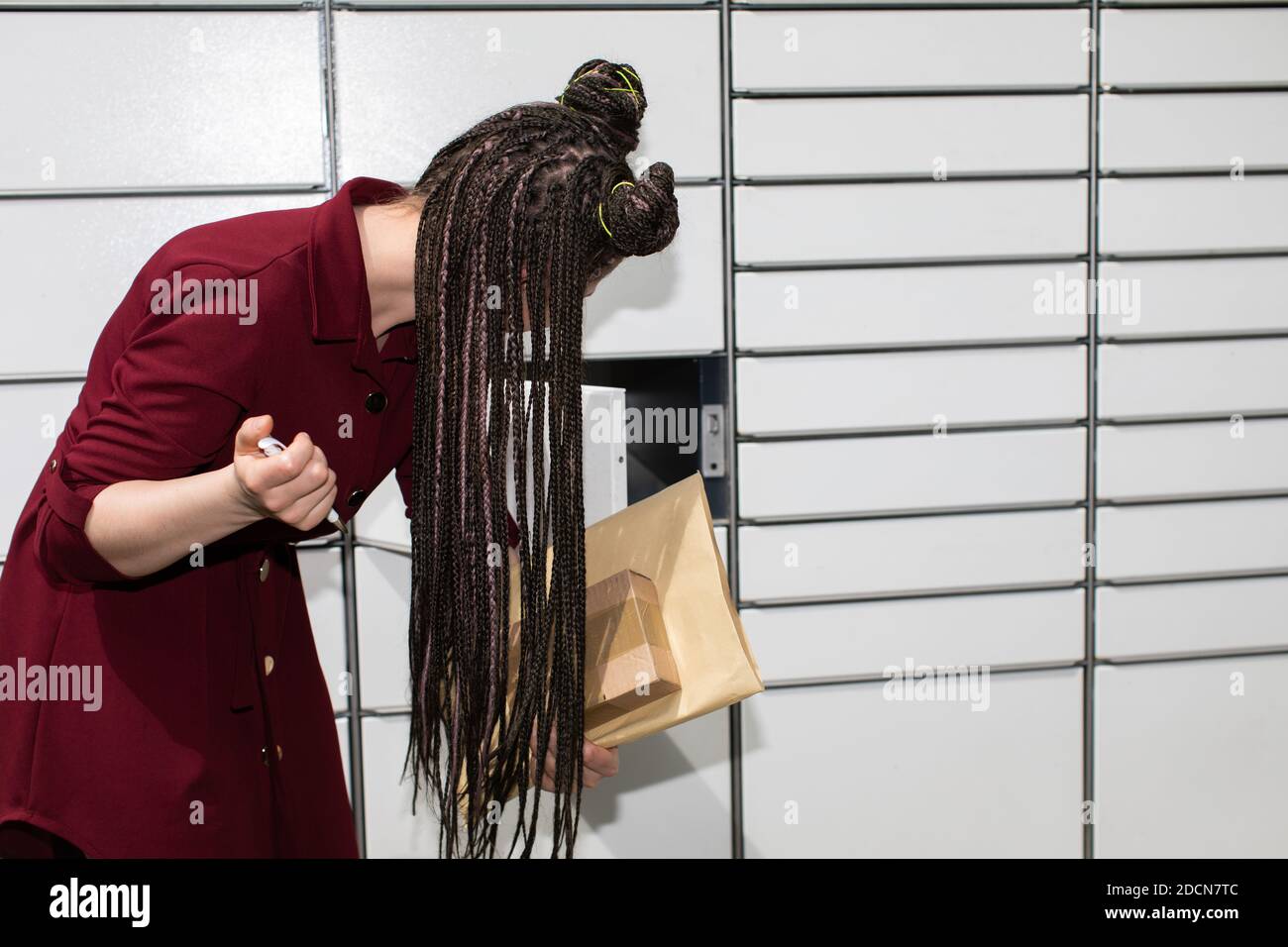 He carefully checks the opened mailbox. Young teenage girl with an interesting hairstyle. African braids. Stock Photo