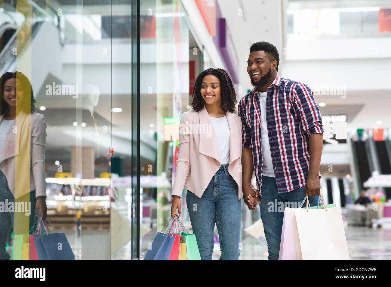 Black Shopaholic Couple Doing Purchases In Mall Together, Enjoying Seasonal Shopping Stock Photo