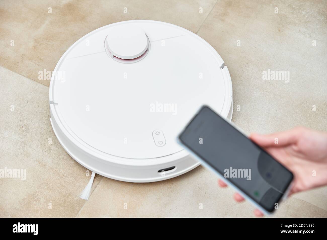 Hand holds smartphone with application control robot vacuum cleaner ...