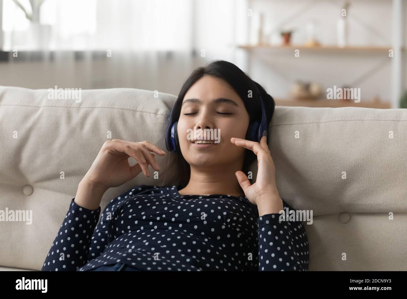 Close up peaceful Asian young woman wearing headphones enjoying music Stock Photo
