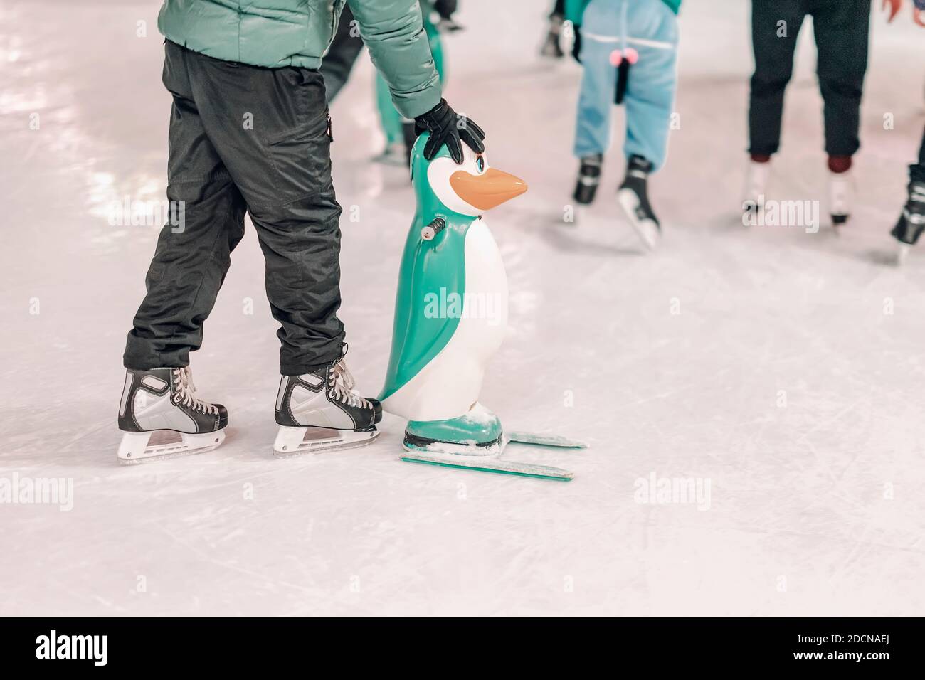 Ice rink. Abstract boy holds a penguin for support and learning to