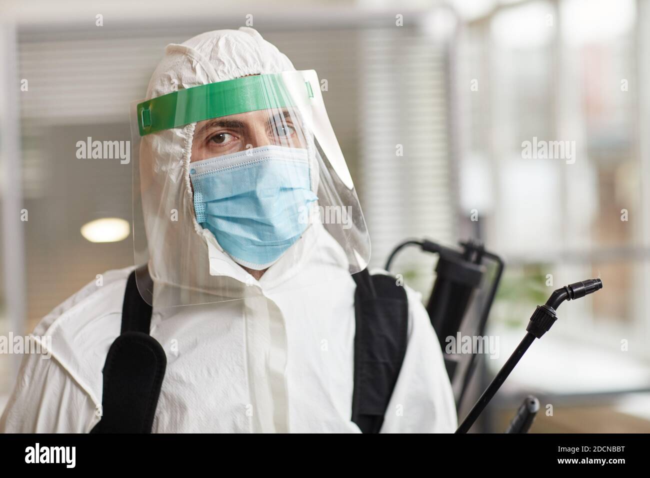 Portrait of male disinfection worker wearing full protective gear and looking at camera while sanitizing office, copy space Stock Photo