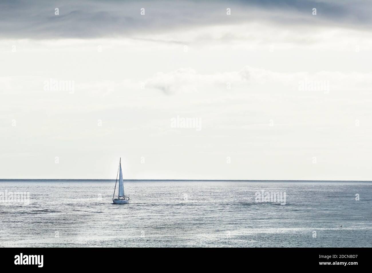 Small sailing boat drifting away from Orkney islands to open Atlantic waters on cloudy day in summer Stock Photo