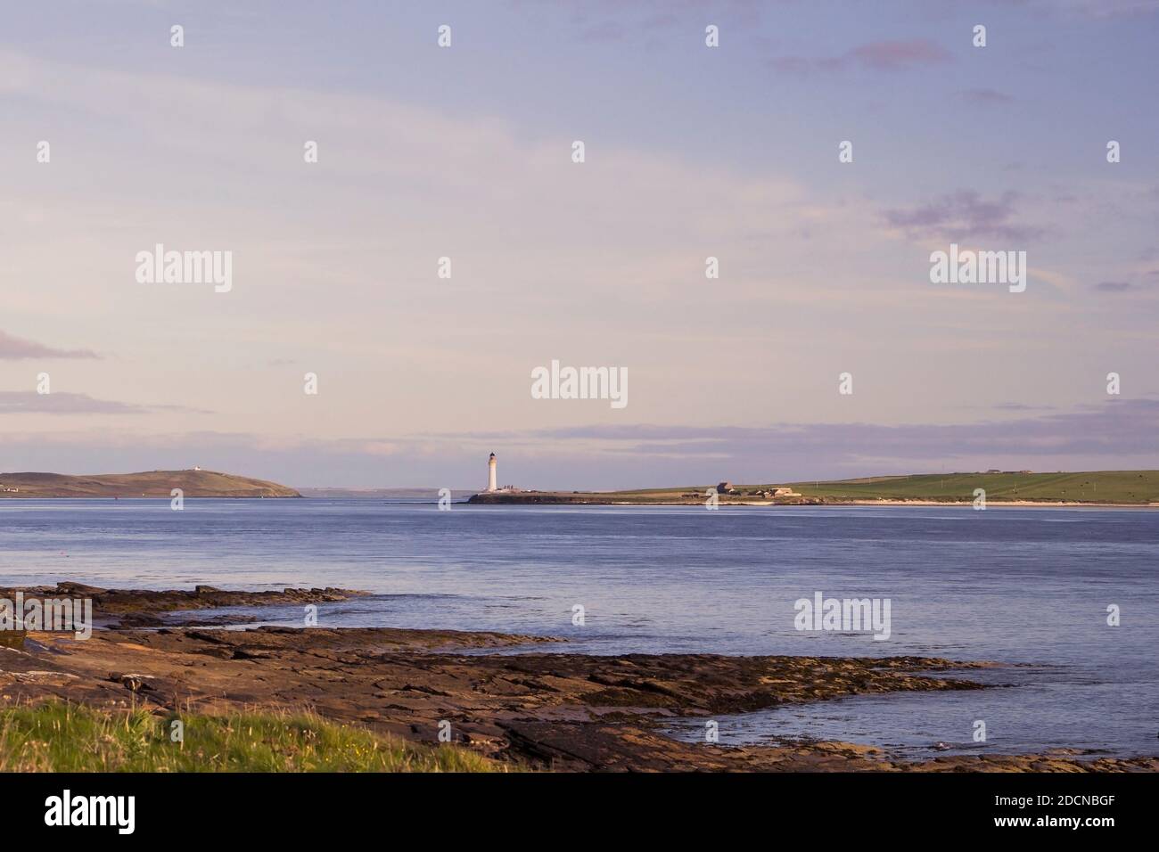 Summer evening view of tall white lighthouse on Orkney island in Scotland Stock Photo