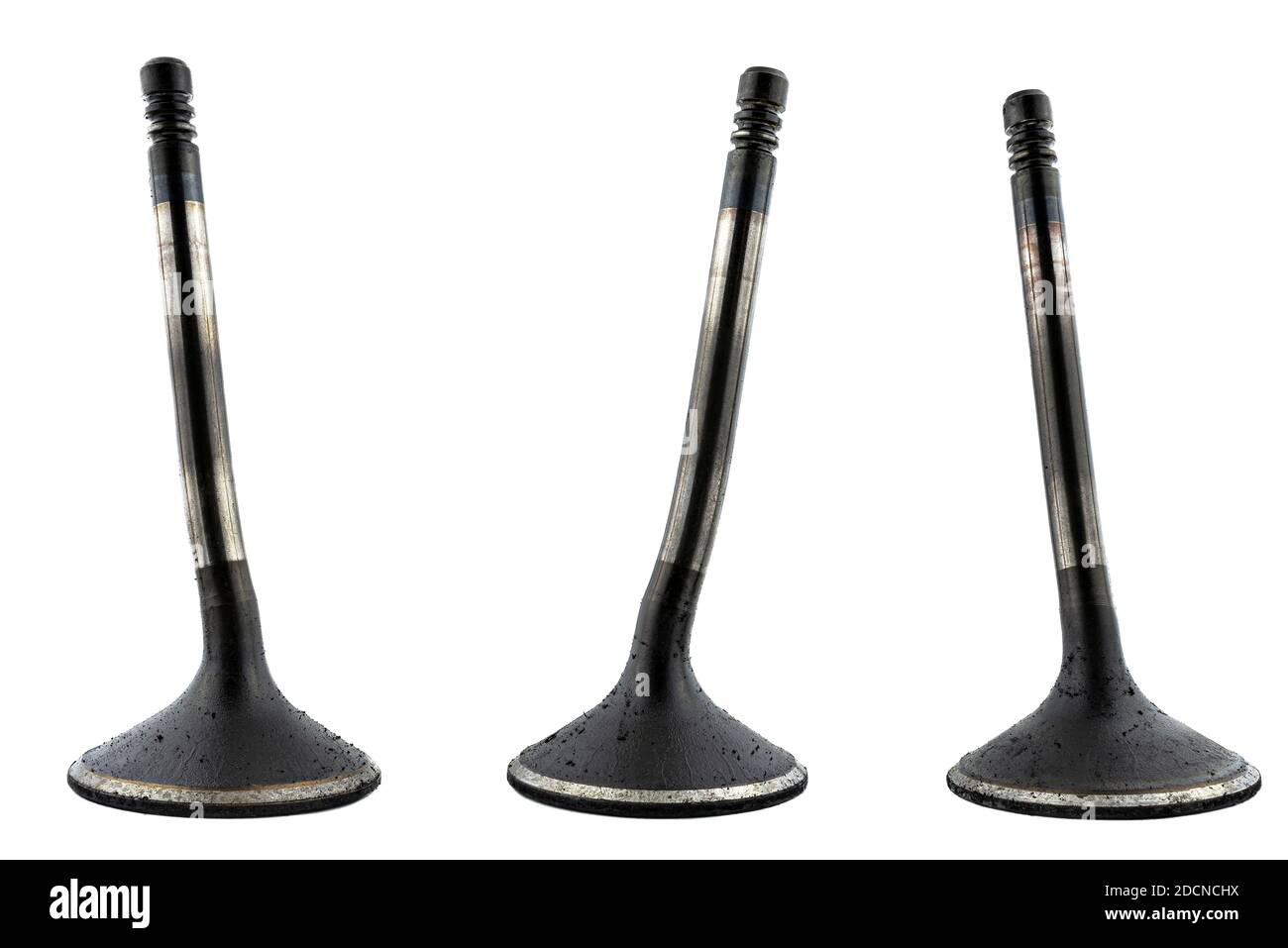 Warped three engine valves, covered with soot, isolated on a white background. Stock Photo