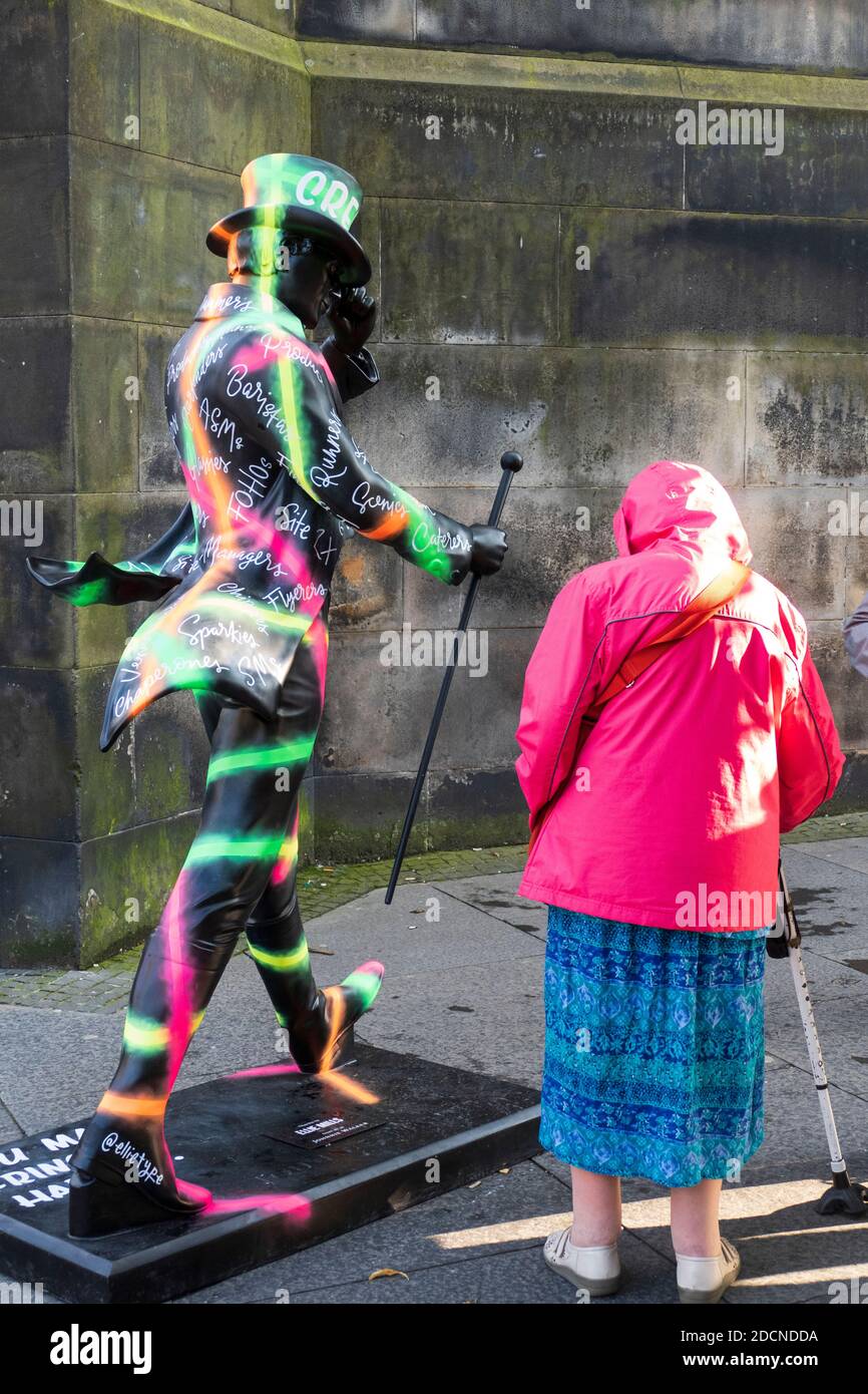 alte Frau mit Gehstock bewundert eine Johnny Walker Figur beim Fringe Festival in Edinburgh Schottland Stock Photo