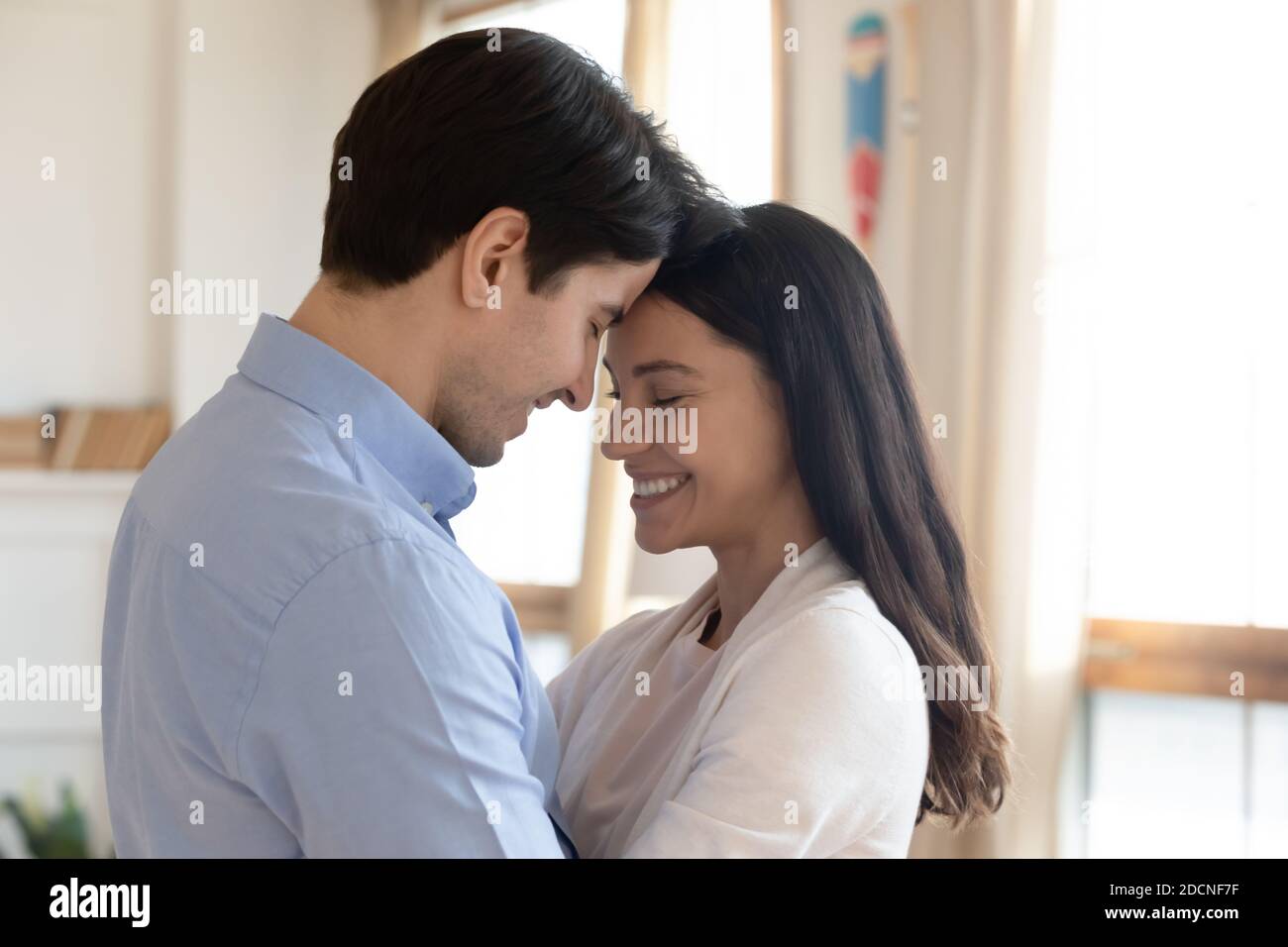 Affectionate couple cuddling with closed eyes spending romantic evening indoors Stock Photo