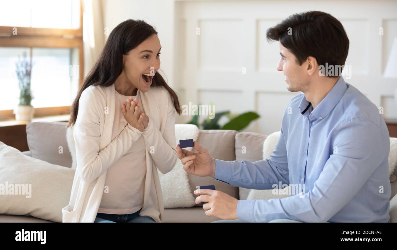 Amazed excited millennial girlfriend receiving marriage proposal from enamored boyfriend Stock Photo