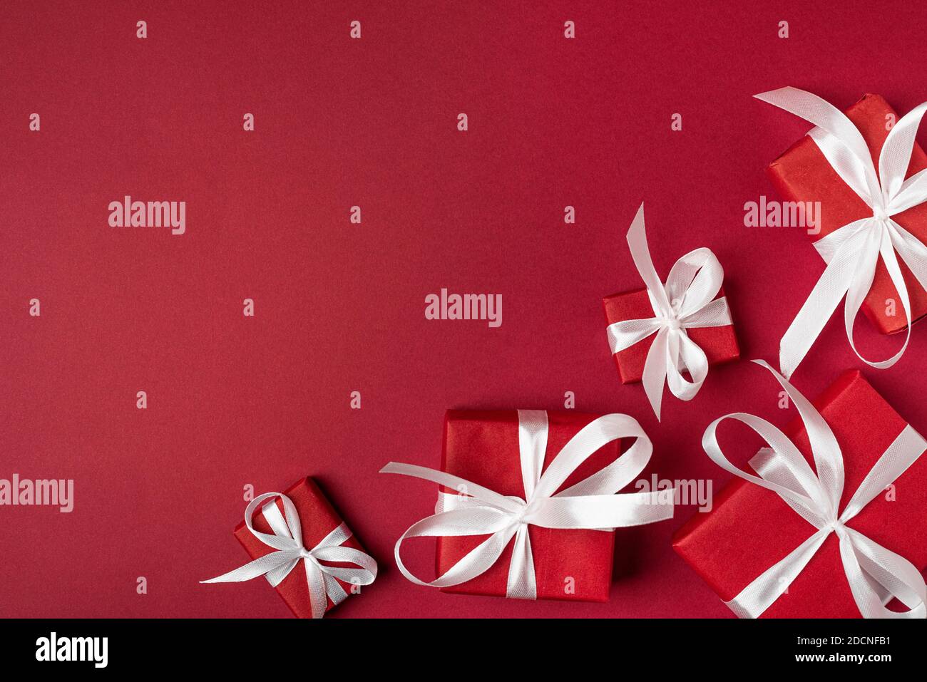Red gifts with white ribbon, present on red background. top view. Happy Holidays. Valentine's day. Birthday. Merry Christmas and Happy New Year Stock Photo
