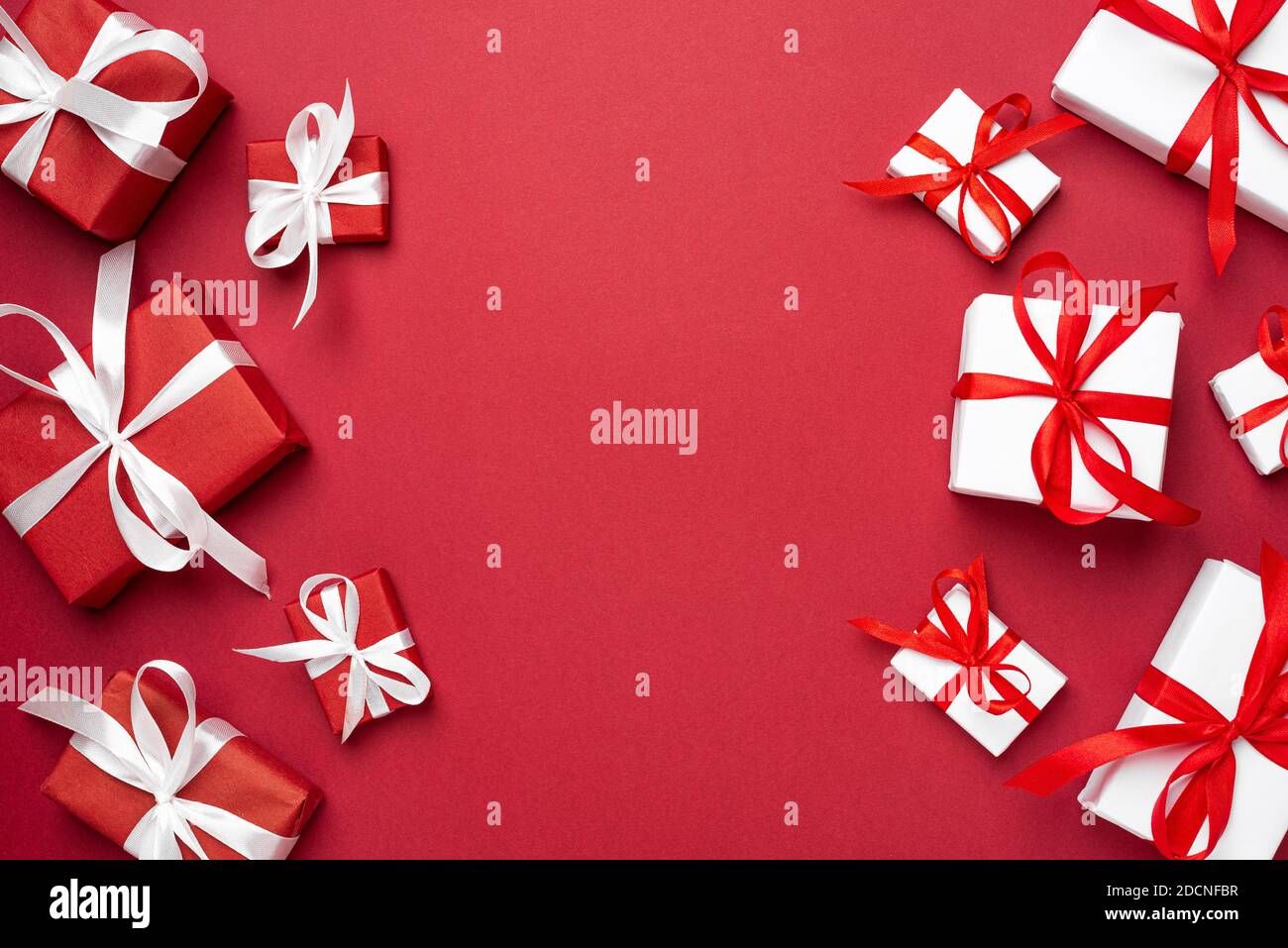 Merry Christmas and Happy Holidays greeting card. New Year. Red and white Christmas gift boxes on red background. top view. Flat lay Stock Photo
