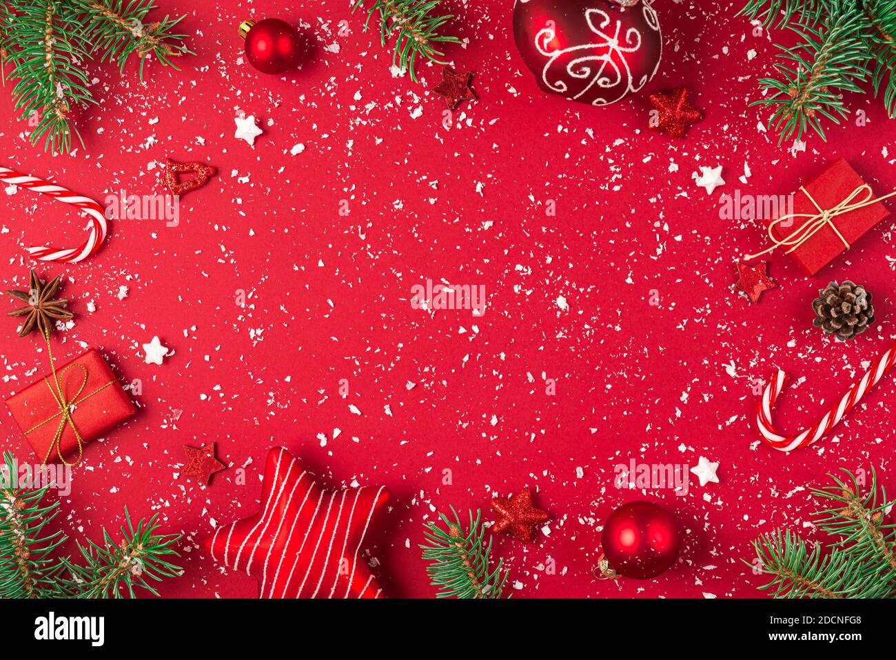 Christmas composition. Frame made of gifts, fir tree, candy, decorations on red background. Christmas, winter, new year concept. Flat lay, top view wi Stock Photo