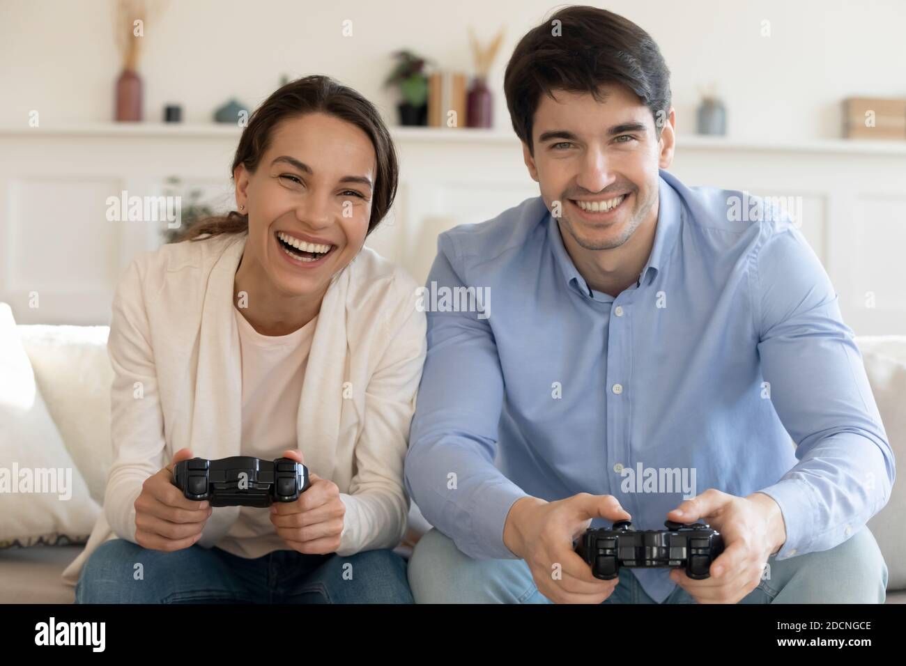 Joyful couple winning video games with joystick on console in