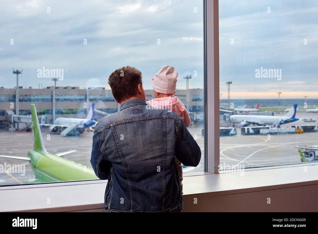 People at the airport. The man and daughter look out the window at the planes Stock Photo