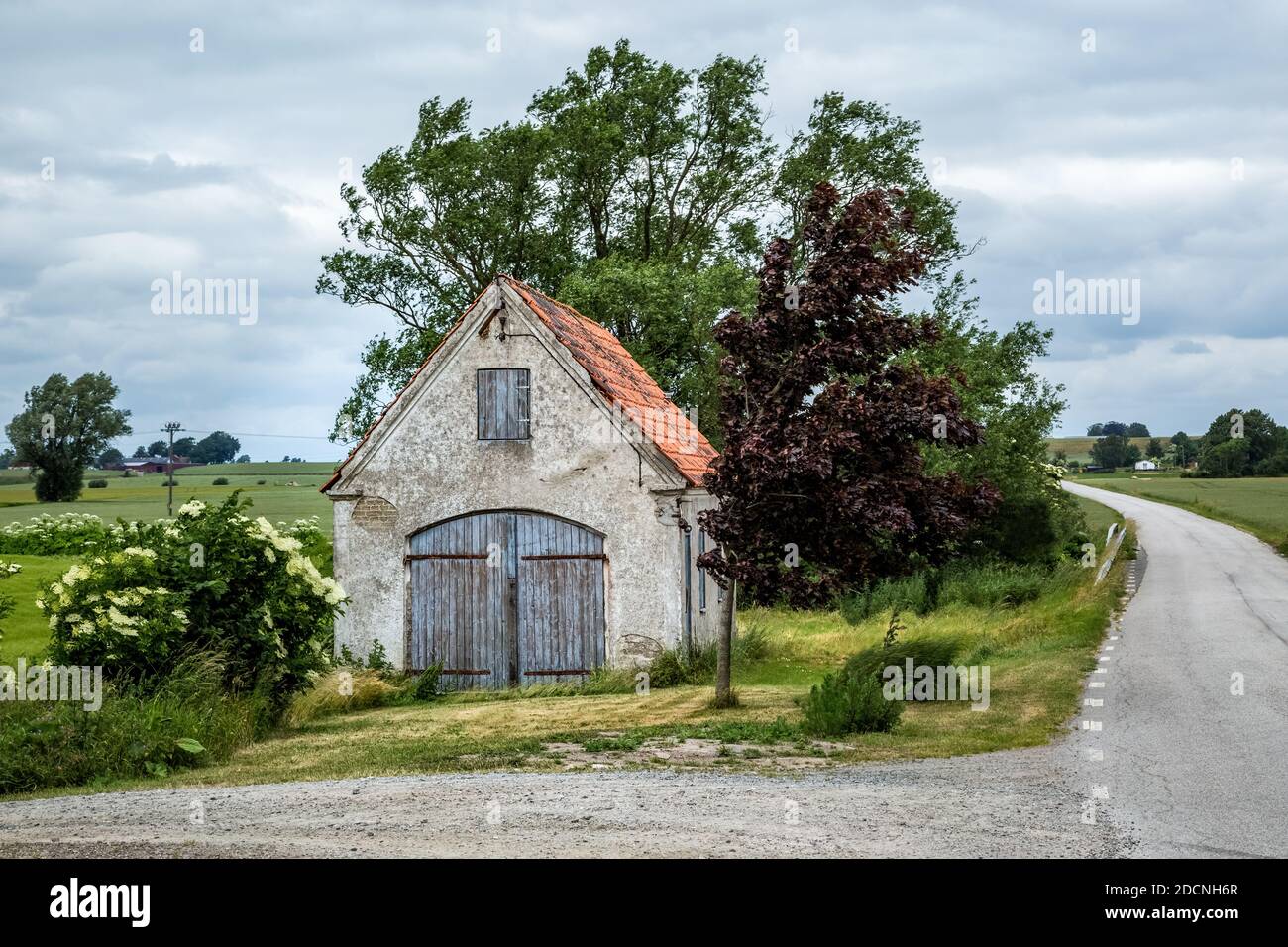 Old weathered brick shed with plaster peeling off next to a small country road in Valleberga, Skane, Southern Sweden. Stock Photo