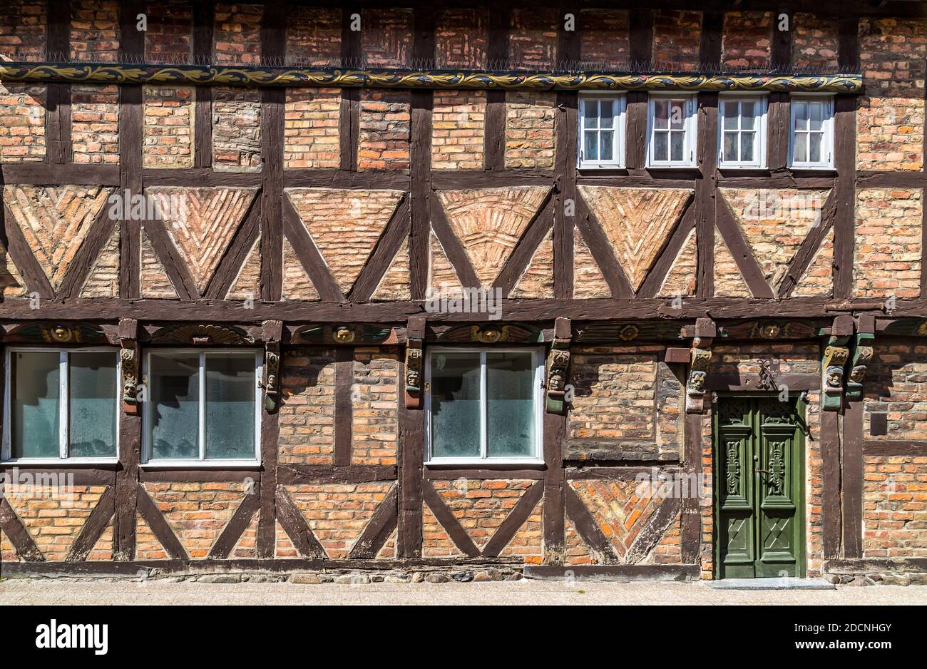 Facade of a historic half timbered house with bricks in various patterns, carved ornaments, and a green door in Ystad, Sweden. Stock Photo