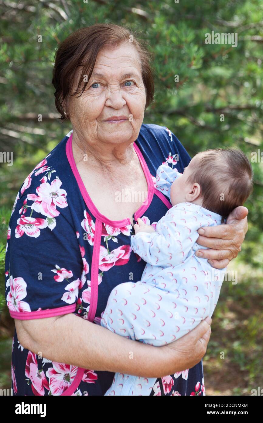 Elderly woman carrying a baby in arms, great grandmother portrait with