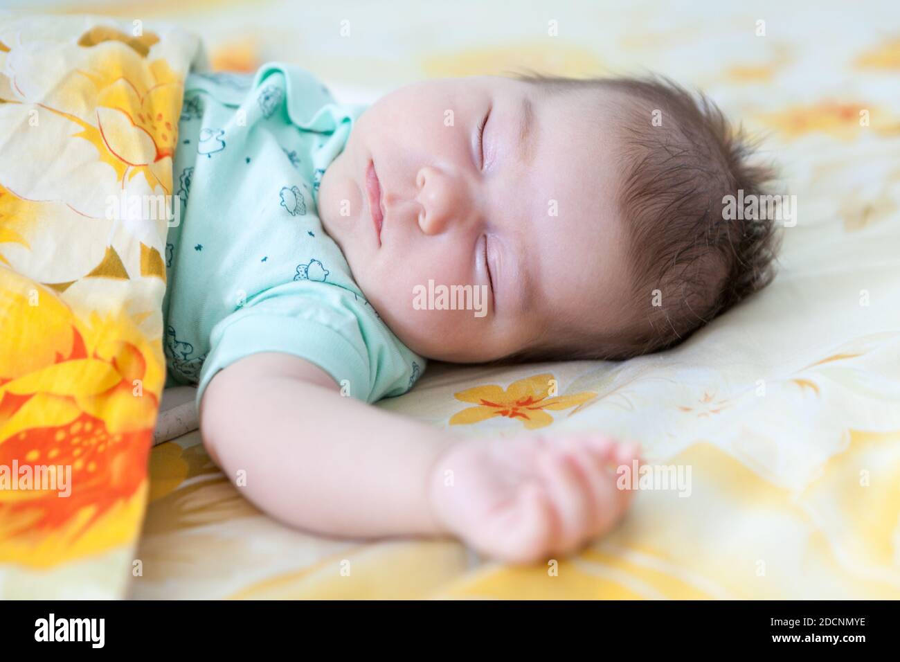 Newborn Caucasian child sleeping in cot covered with blanket, close up