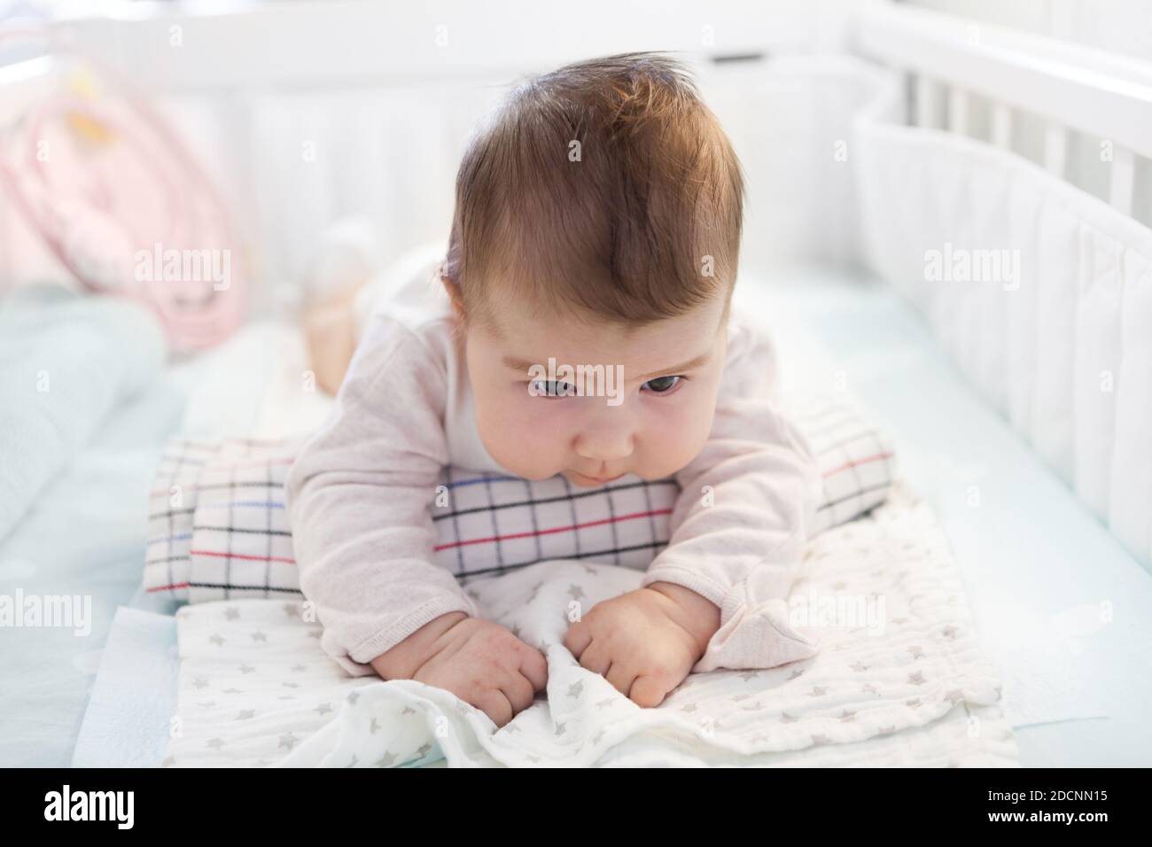 Baby two month old trying to hold head leaning rolled towel, lying in a