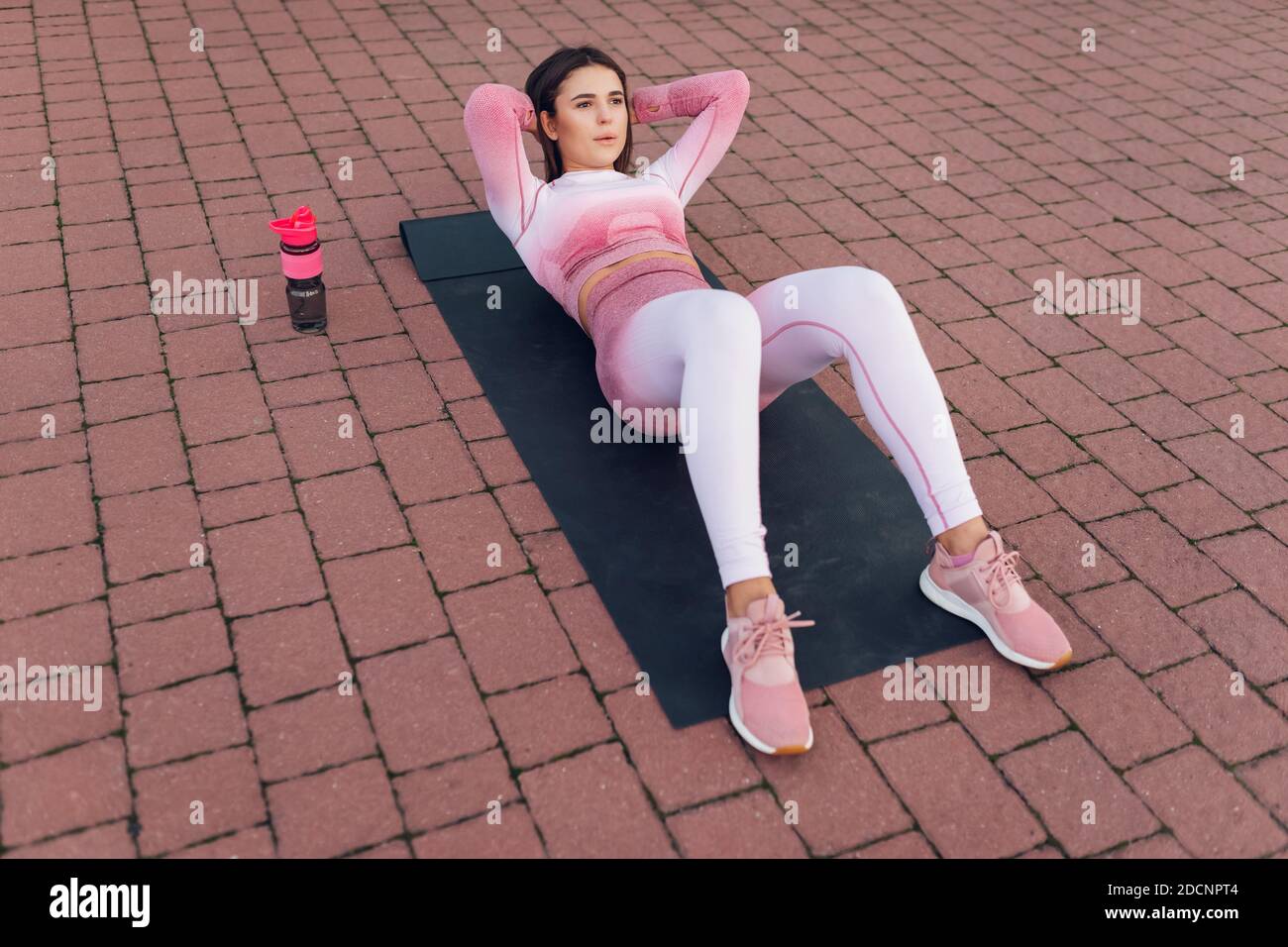 Beautiful Fitness Woman In Pink Sportswear Lying On Yoga Mat And Doing Abdominal Crunch Exercise